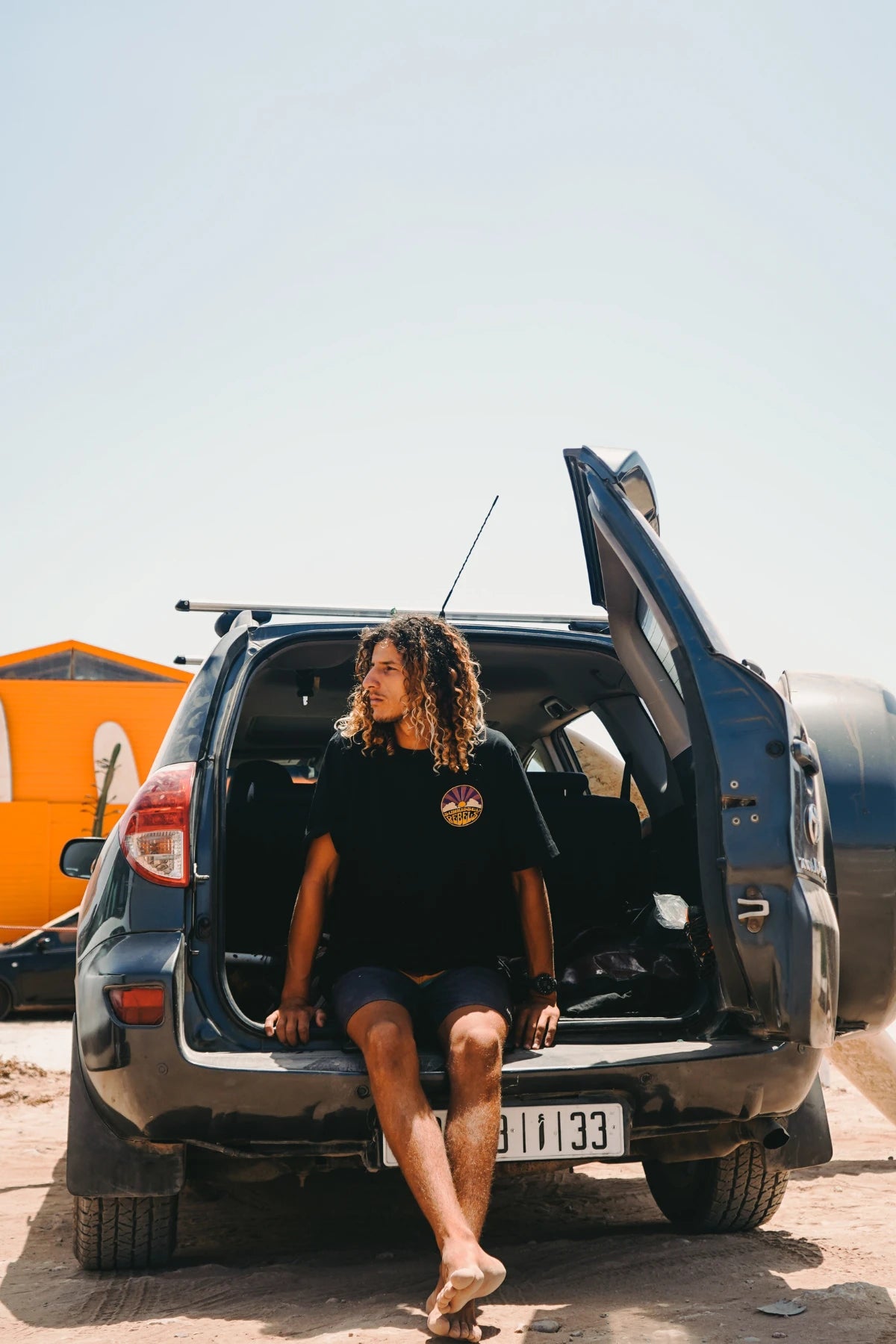 Chilliger Surfer im Sunkissed Rebels Shirt auf SUV-Heck