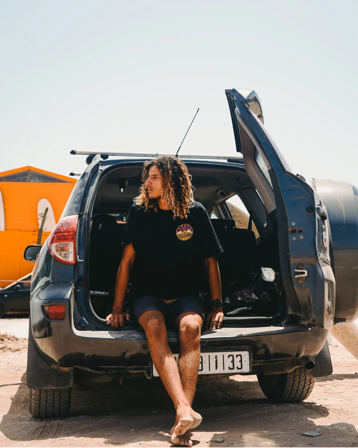Chilliger Surfer im Sunkissed Rebels Shirt auf SUV-Heck
