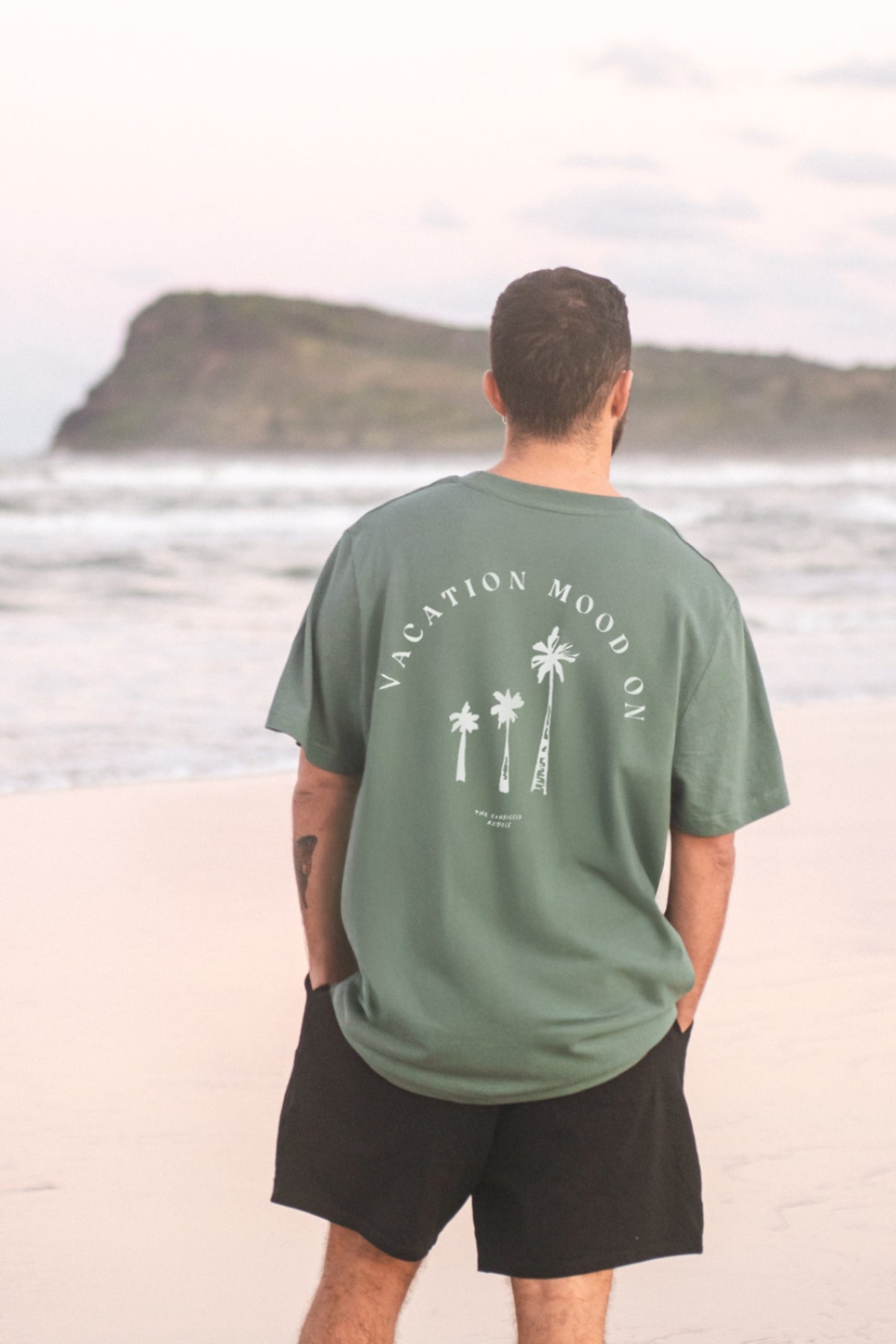 Mann schaut auf das Meer und trägt das Vacation Mood On T-Shirt in Green Bay von The Sunkissed Rebels