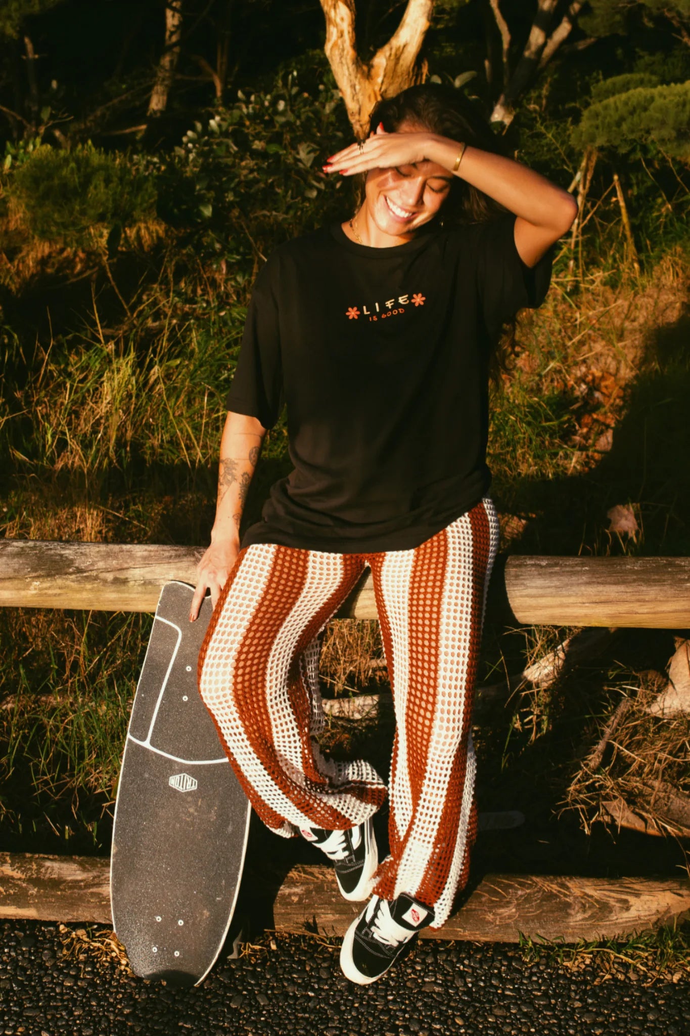 Frau im schwarzen Oversized T-Shirt sitzt entspannt im Sonnenlicht und trägt ein lässiges Sommer Outfit