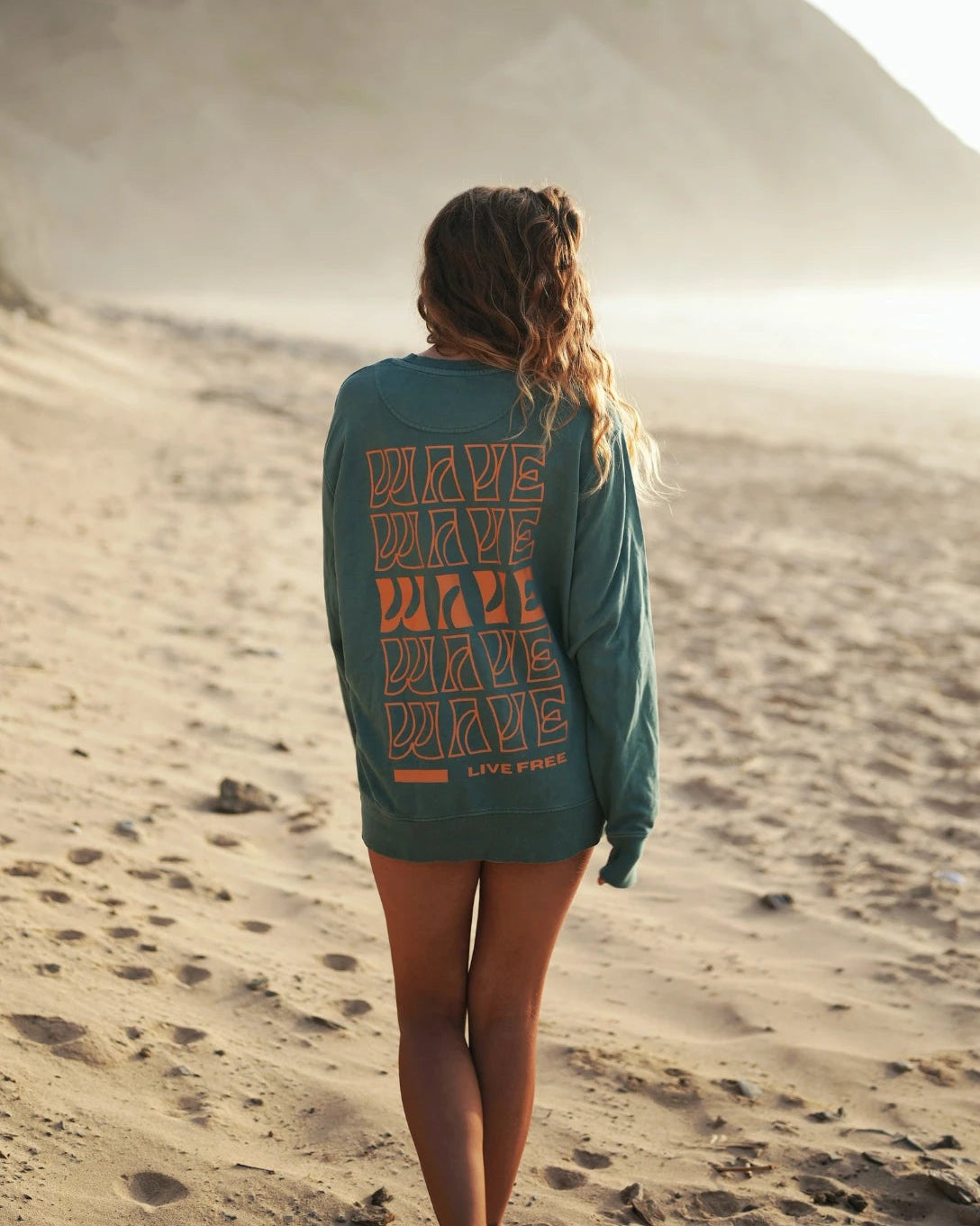 Palm Green Sweater von hinten – Frau blickt Richtung Sonnenuntergang