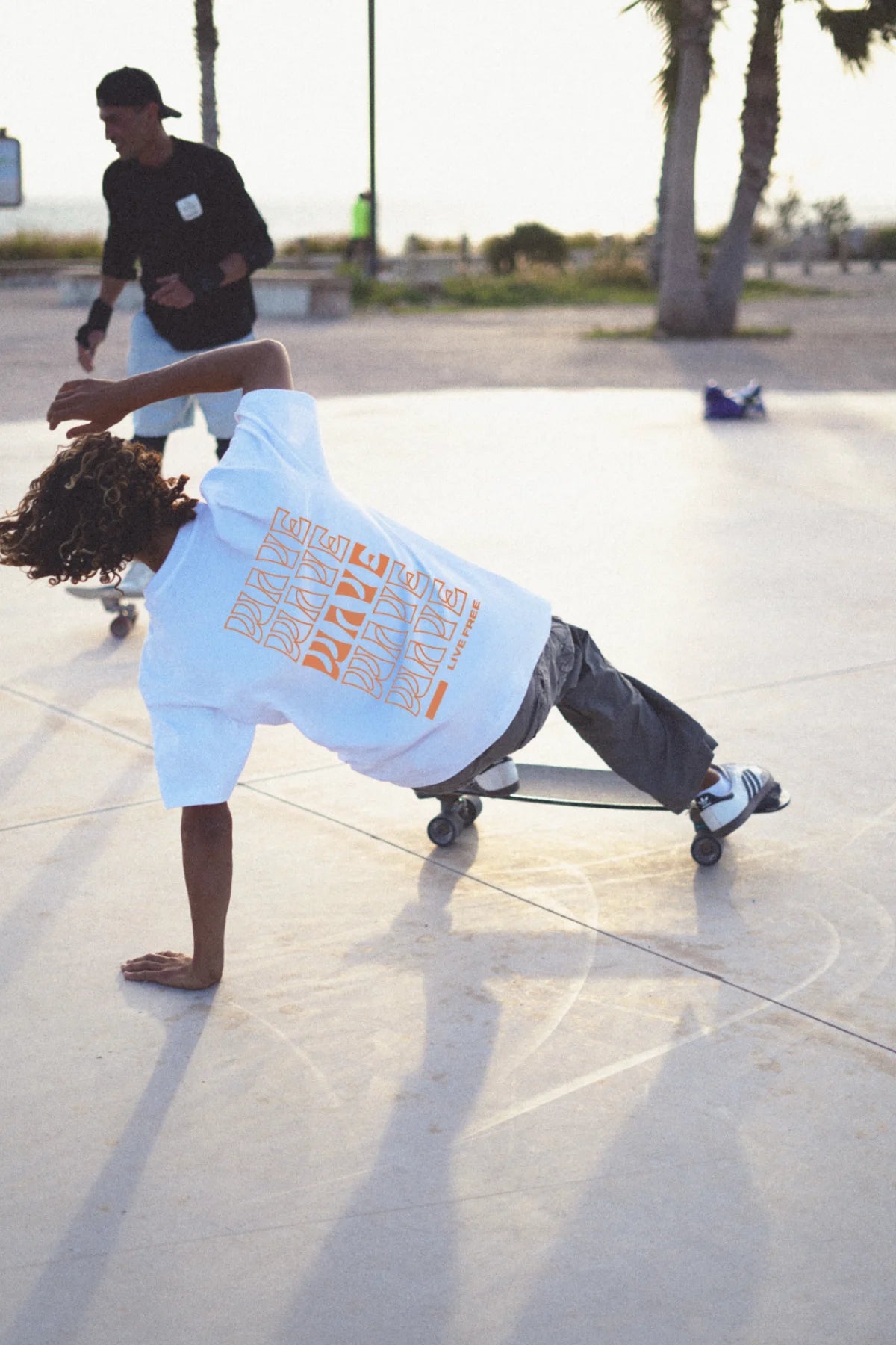 Skater im weißen Live Free T-Shirt beim Trick im Skatepark – Urban Summer Vibes