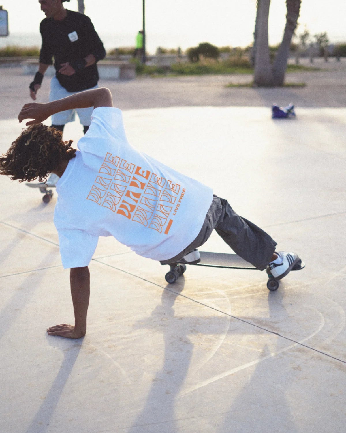 Skater im weißen Live Free T-Shirt beim Trick im Skatepark – Urban Summer Vibes