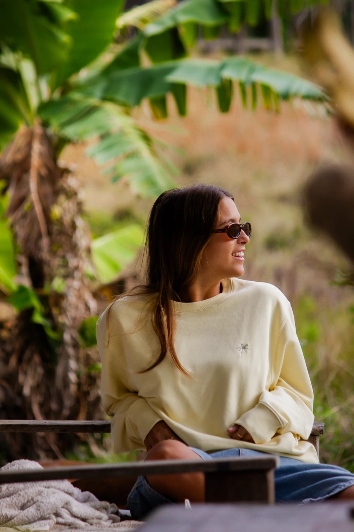 Blick zur Seite im butterfarbenen Palm Tree Sweater mit Sommer-Vibes im Grünen