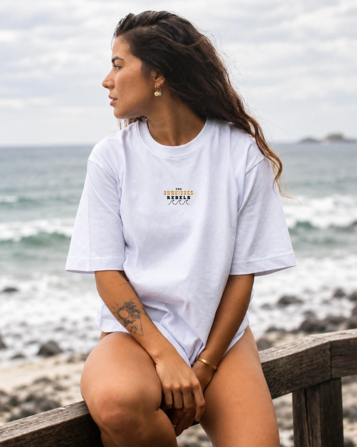 Frau trägt das Paradise & Sunsets Oversized T-Shirt in White im entspannten Coastal Look am Strand