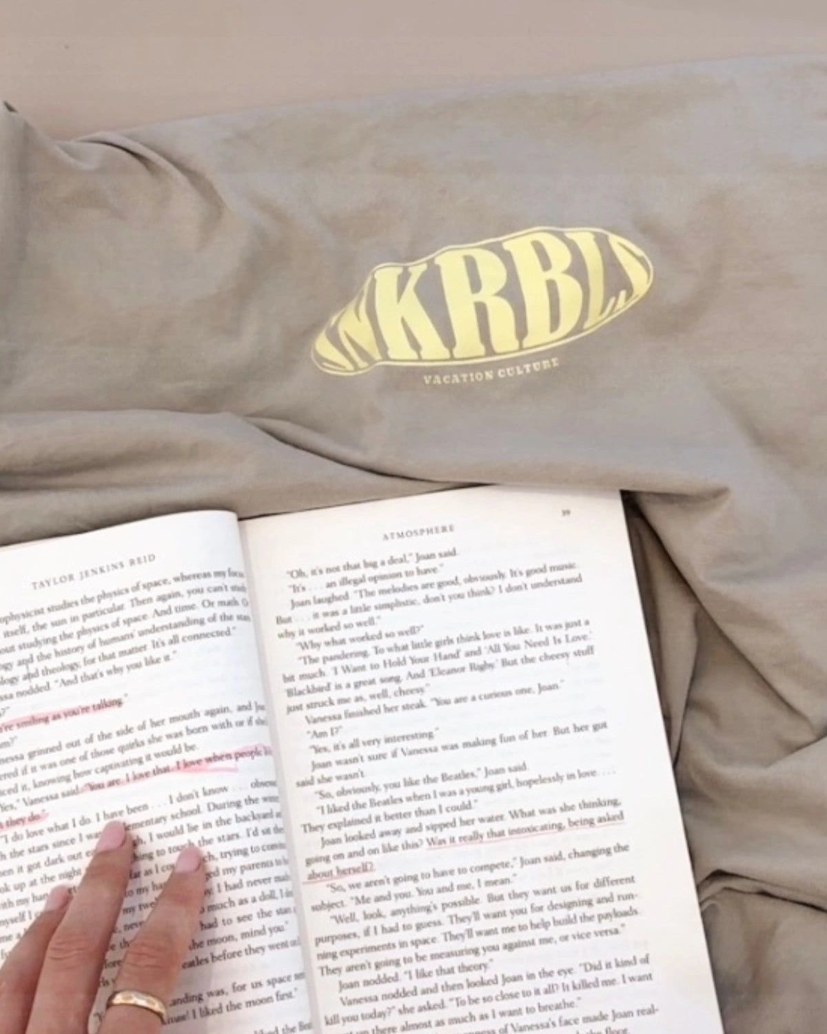 T-Shirt in Beige mit KRBL-Print neben einem Buch – Cozy Vibes & Vacation Mood