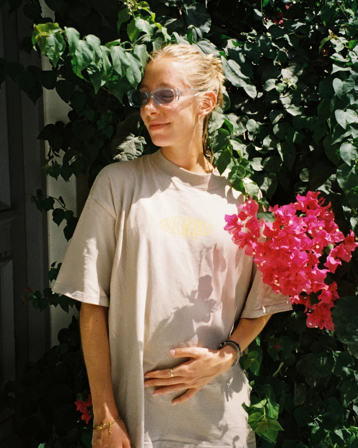 Frau im Oversized Shirt vor blühender Pflanze – sommerlicher Streetstyle