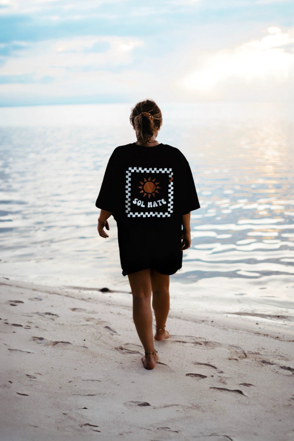 Model spaziert am Meer mit Sol Mate T-Shirt – The Sunkissed Rebels Kollektion