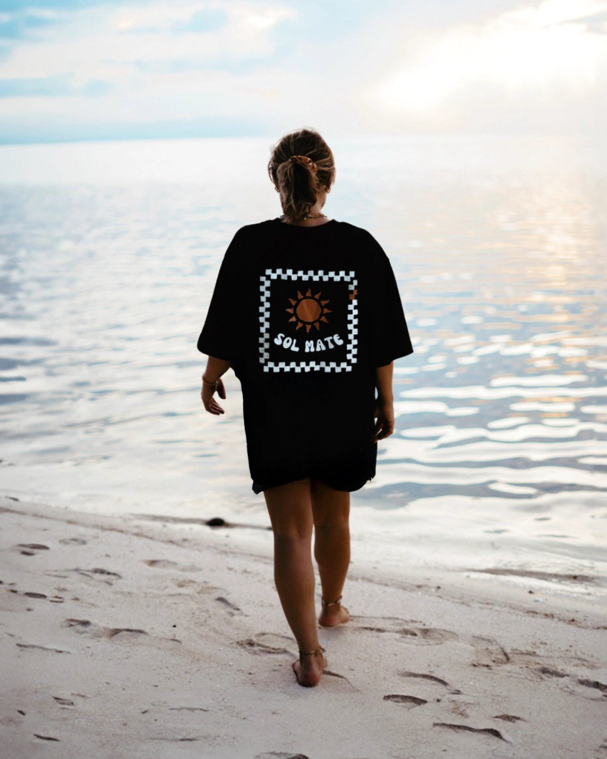 Model spaziert am Meer mit Sol Mate T-Shirt – The Sunkissed Rebels Kollektion