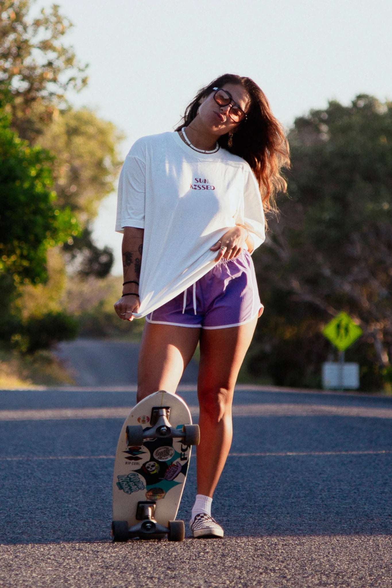 Frau läuft mit Skateboard und trägt Sunkissed Light T Shirt Natural Raw im Sonnenlicht