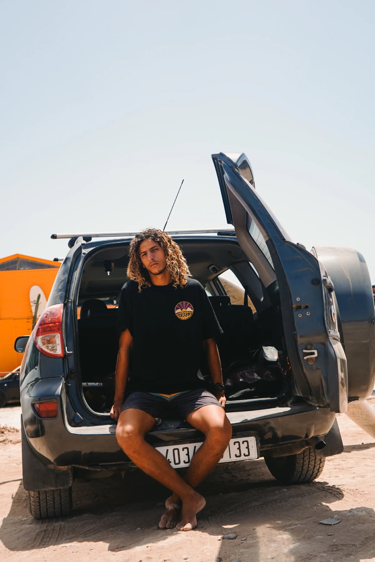 Surfer sitzt entspannt im Kofferraum – Sunkissed Rebels Feeling