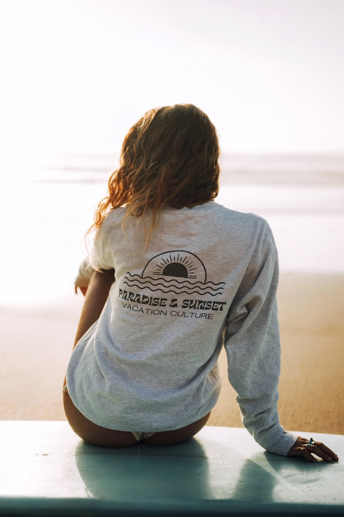 Rückenansicht vom Paradise & Sunset Sweater am Strand bei Sonnenuntergang