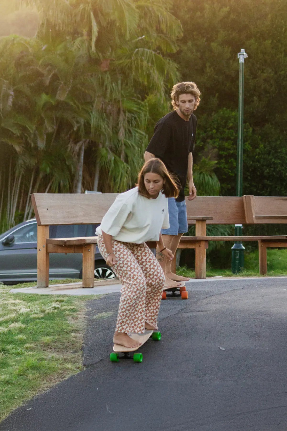 Skateboard-Couple trägt The Sunkissed Rebels T-Shirts in Creme & Schwarz – sportlicher Streetstyle
