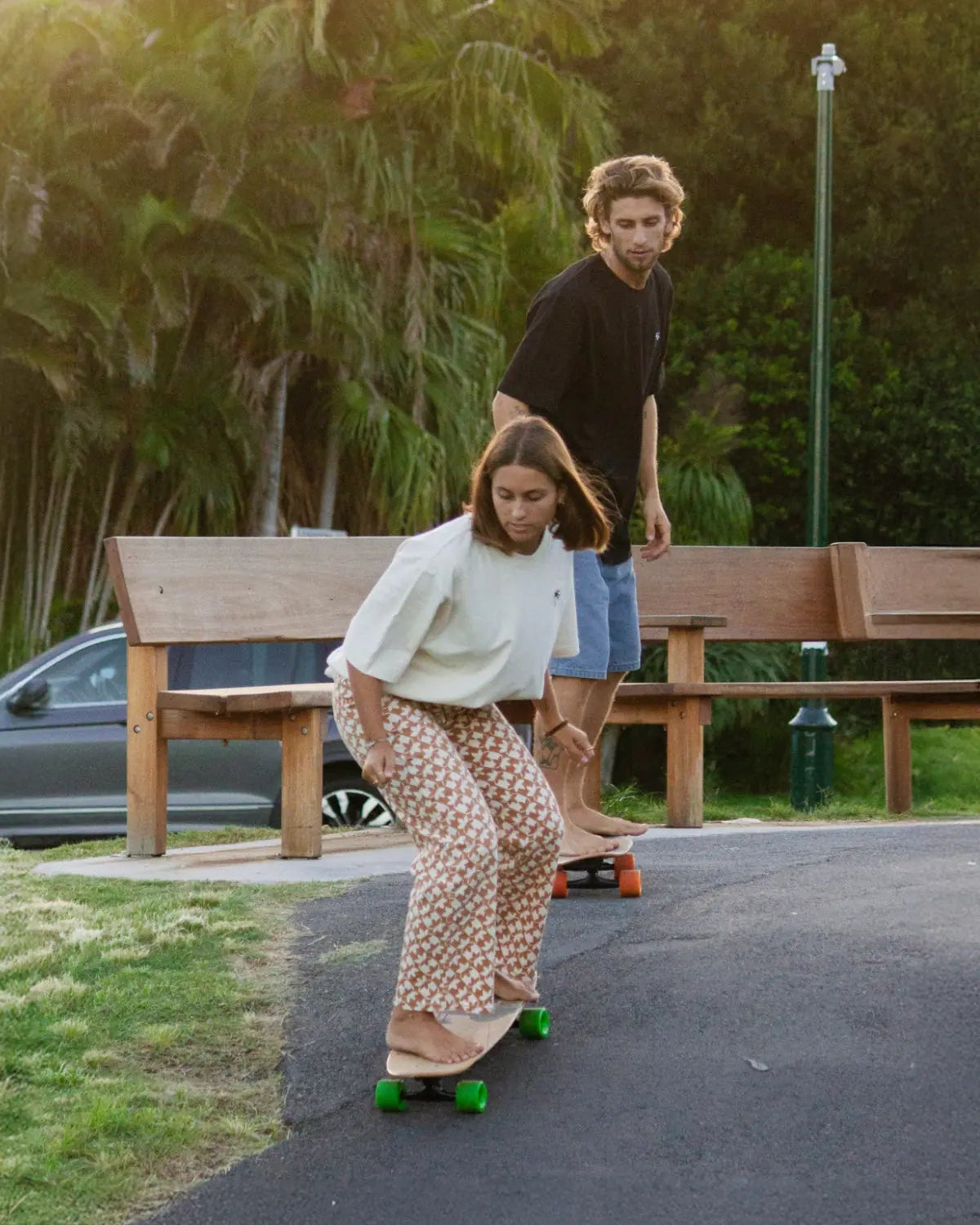 Skateboard-Couple trägt The Sunkissed Rebels T-Shirts in Creme & Schwarz – sportlicher Streetstyle