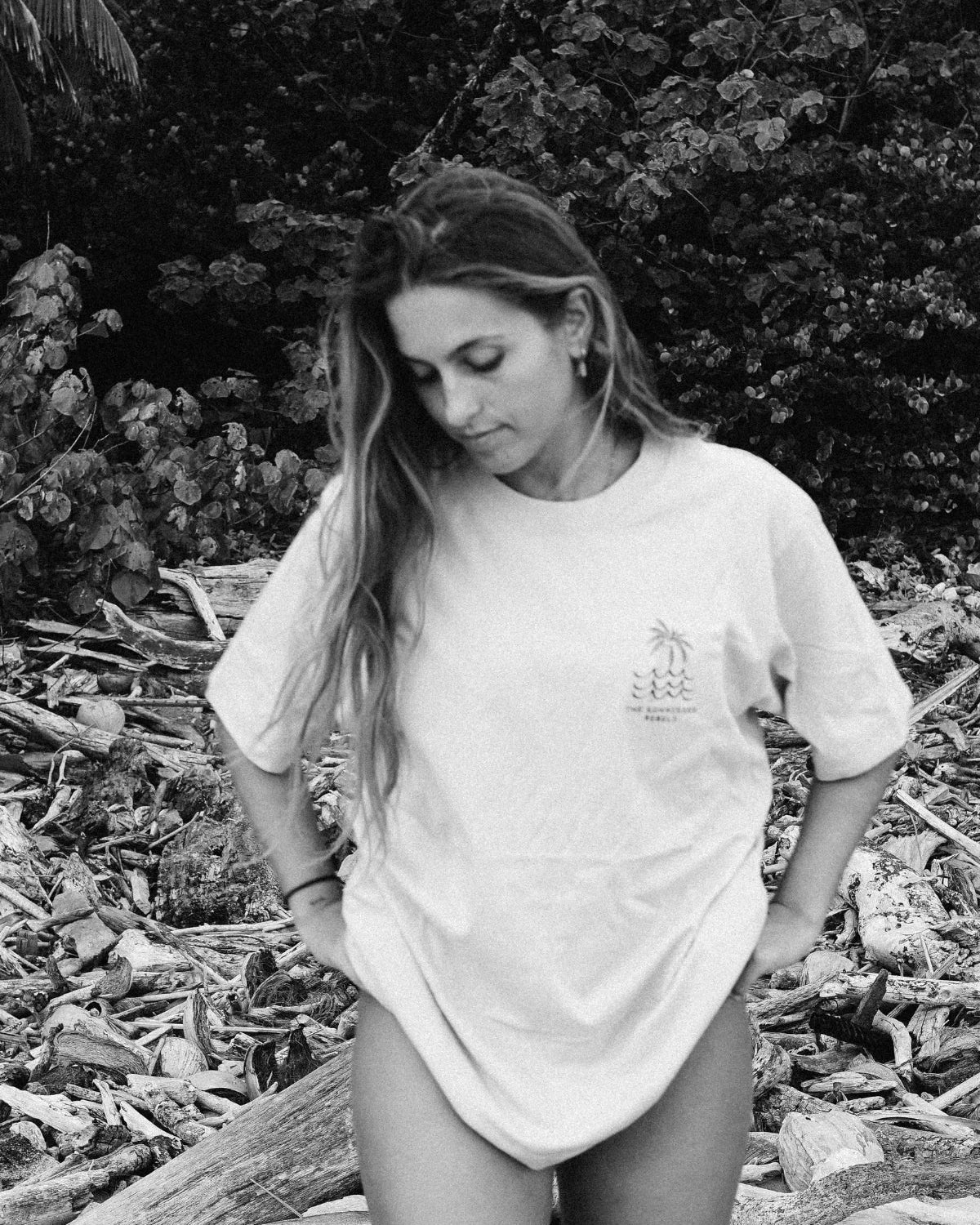 Frau trägt das Waves & Palm Trees Oversized T-Shirt in Sand am Strand in einer stimmungsvollen Schwarz-Weiß-Aufnahme.