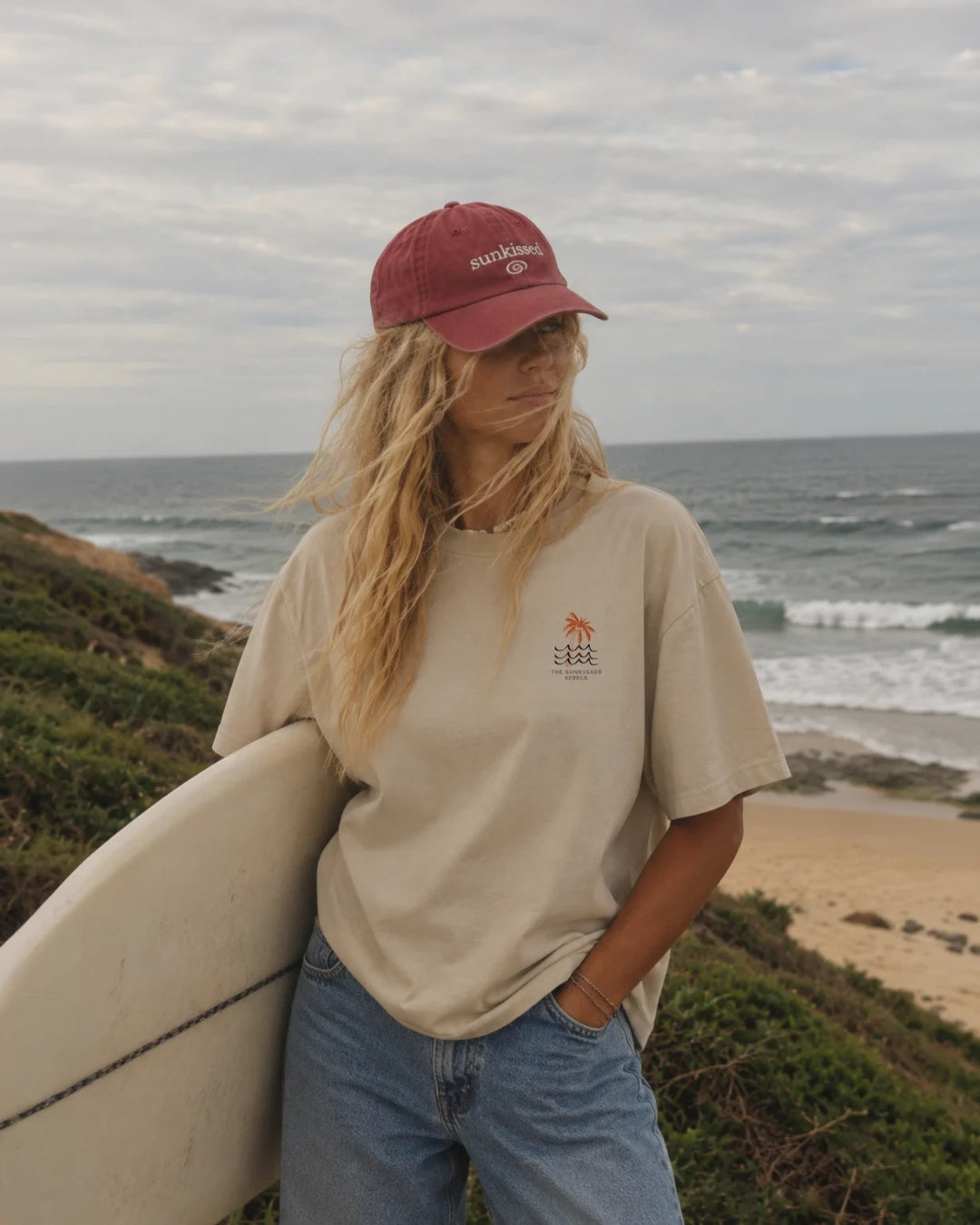 Frau trägt Waves and palm Tree oversized T-shirt am Strand von The Sunkissed Rebels