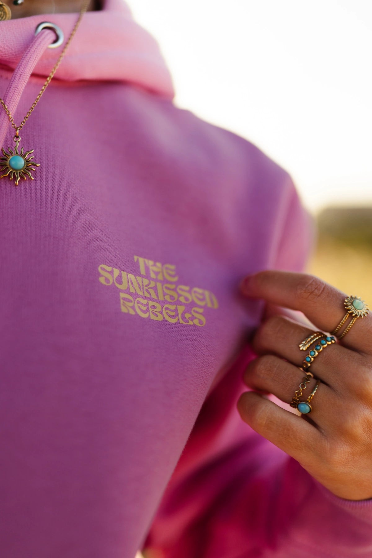 Detailaufnahme des A Good Day Hoodie Bubble Pink mit Brustlogo und Skateboard im Gegenlicht.