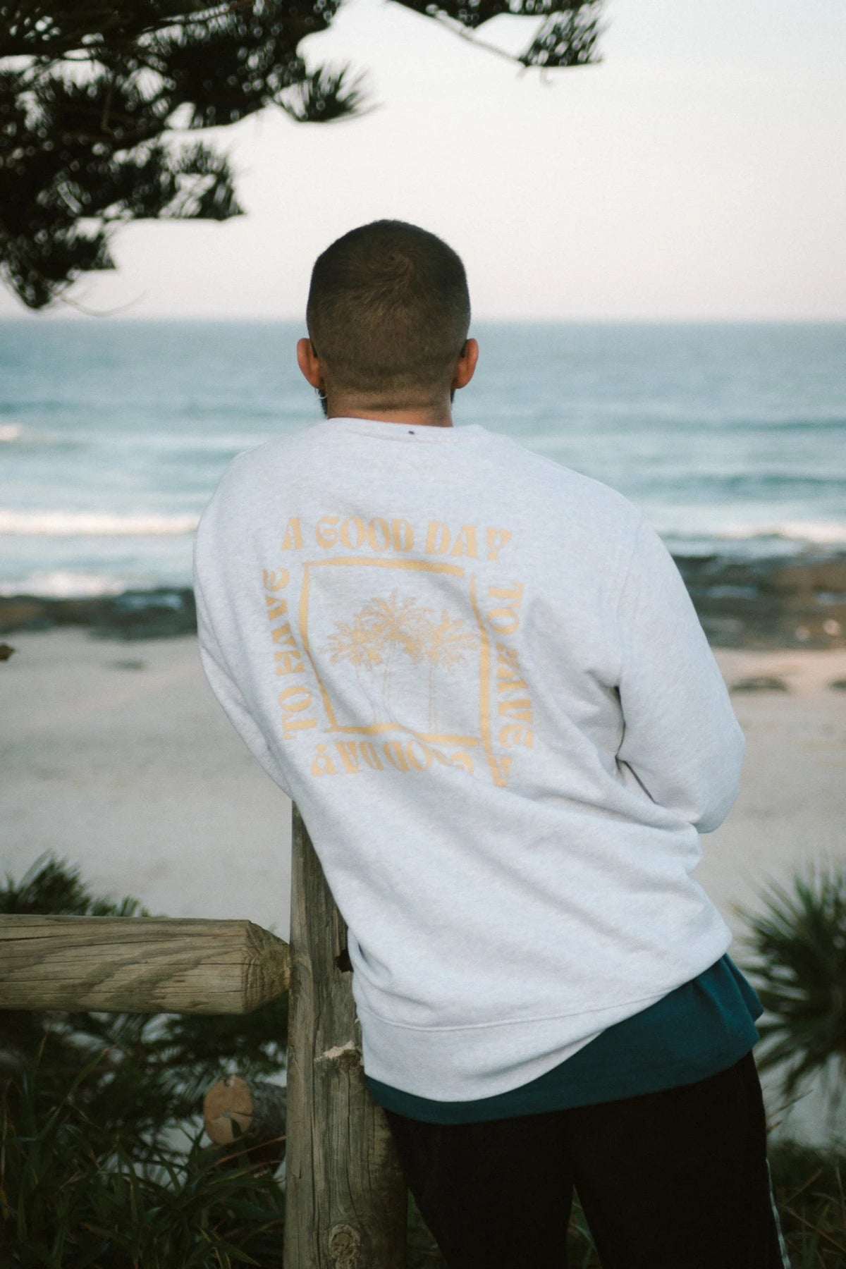 Modefoto eines Mannes mit Sonnenbrille im A Good Day Sweater Cool Grey von The Sunkissed Rebels, aufgenommen an der Küste.