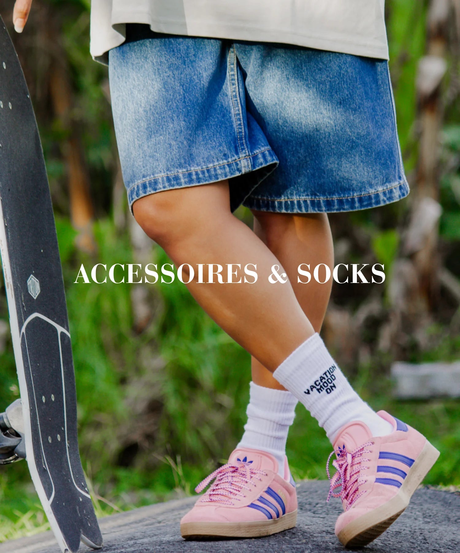 Skater-Style mit weißen ‘Vacation Mood On’ Socken und pink-lila Sneakers – Accessoires & Socken im Fokus vor tropischer Kulisse