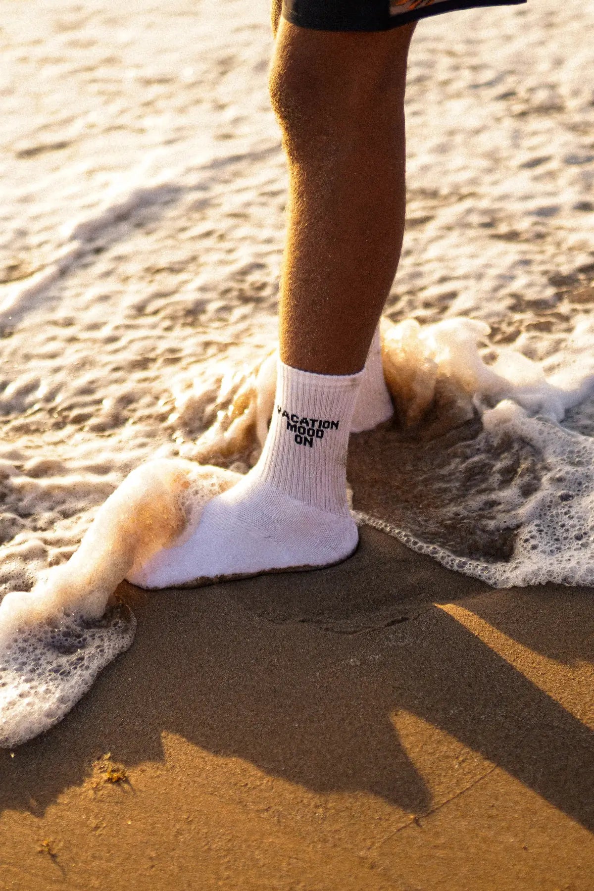 Weiße Vacation Mood On Tennissocken im Sand, umspült von Wellen – sommerlicher Beach-Look mit Statement