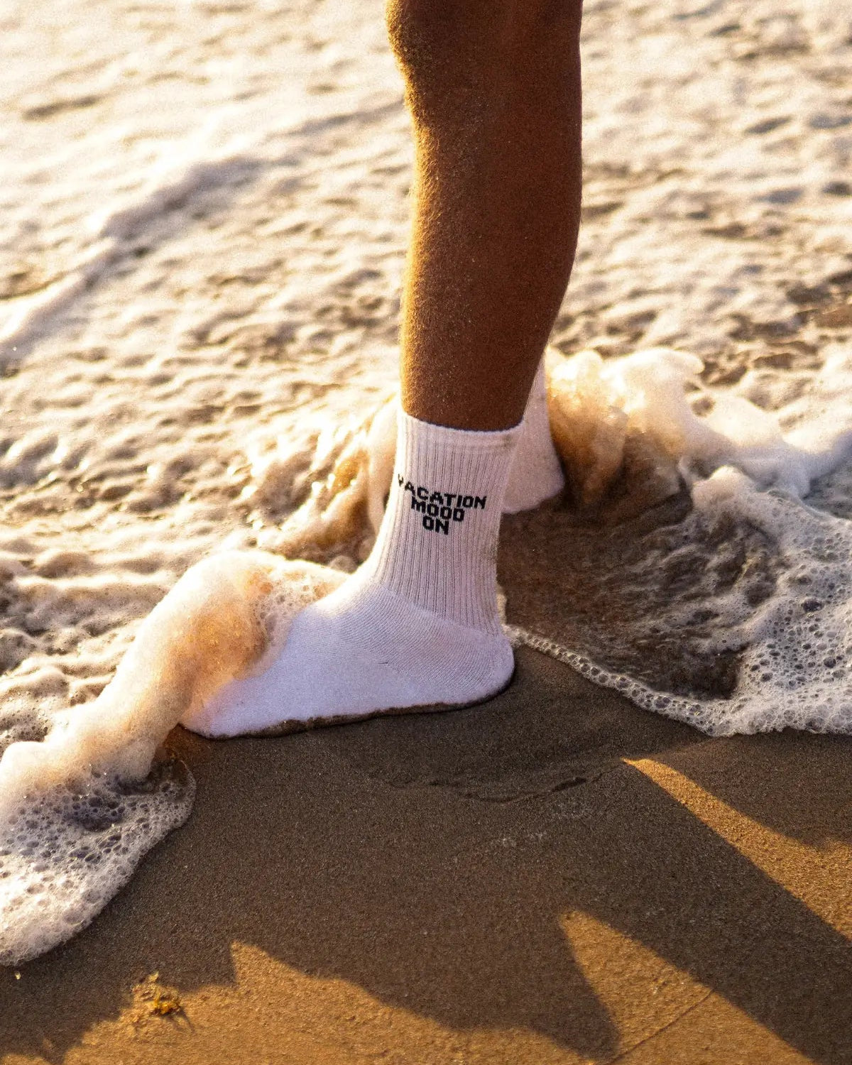 Weiße Vacation Mood On Tennissocken im Sand, umspült von Wellen – sommerlicher Beach-Look mit Statement