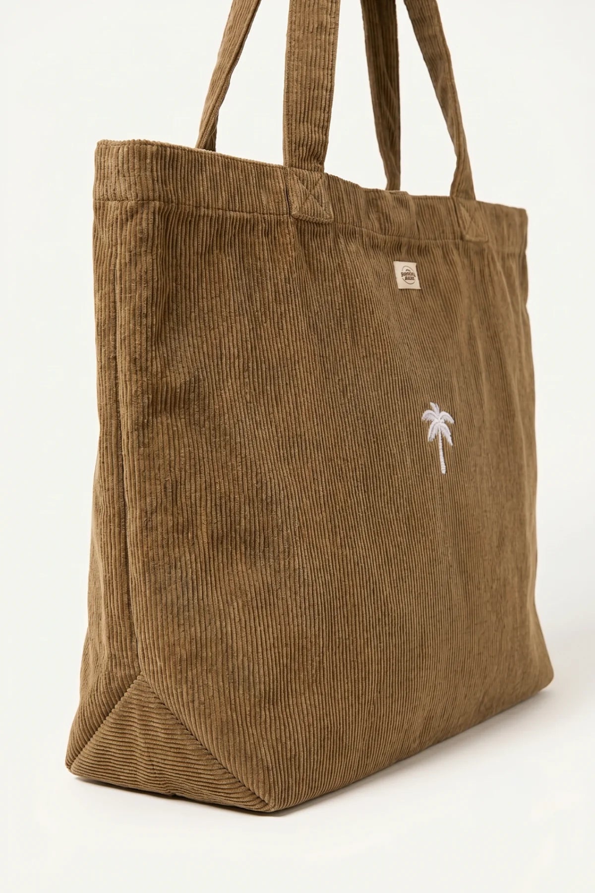 Seitenansicht der geräumigen Palm Tree Cord Bag aus braunem Feincord, die das Volumen und die Bodenfalte zeigt.