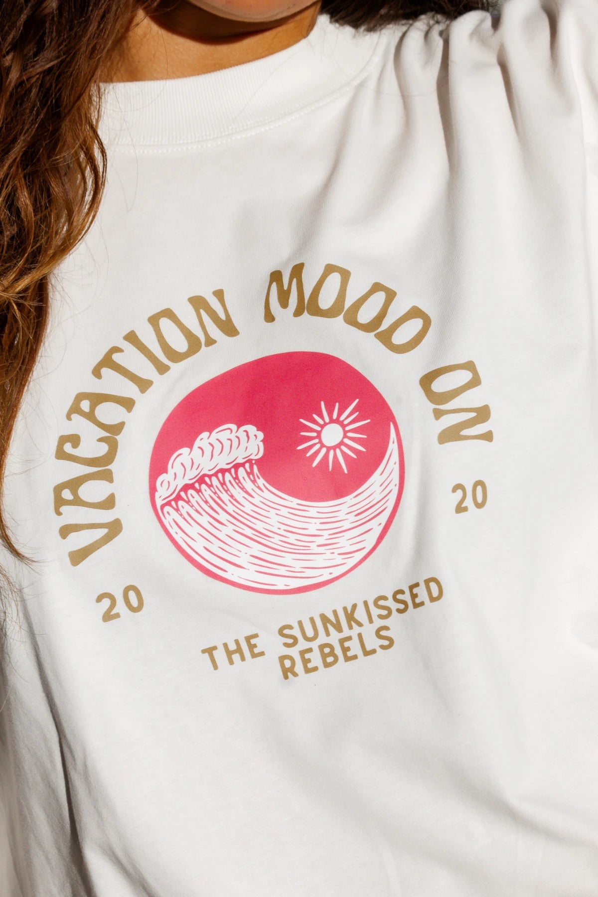 Detailaufnahme des pinken Wellenprints mit Sonne auf dem "Vacation Mood On" Shirt