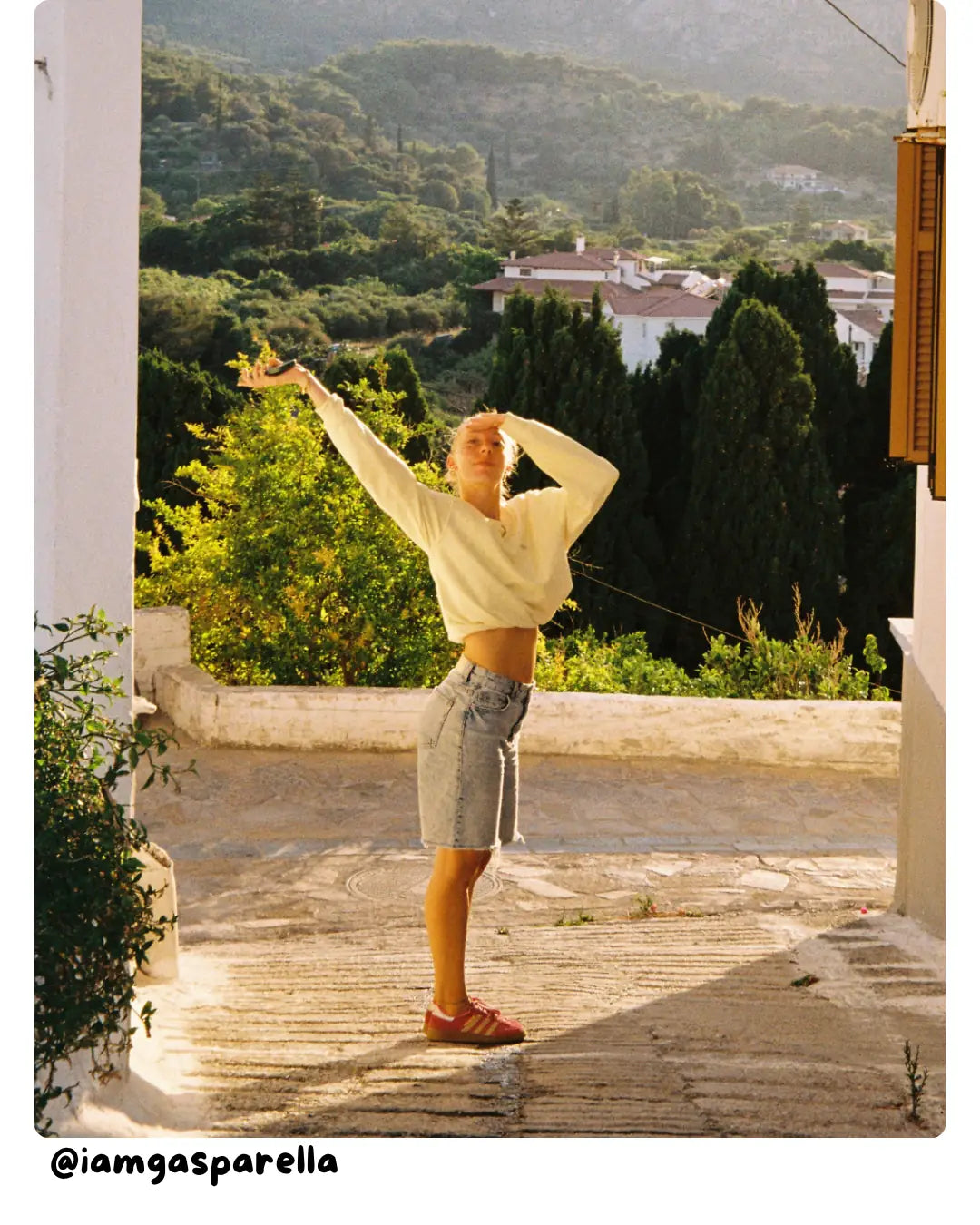 Summer Look von the sunkissed rebels in gelbem Sweater und Denim Shorts vor mediterraner Landschaft.