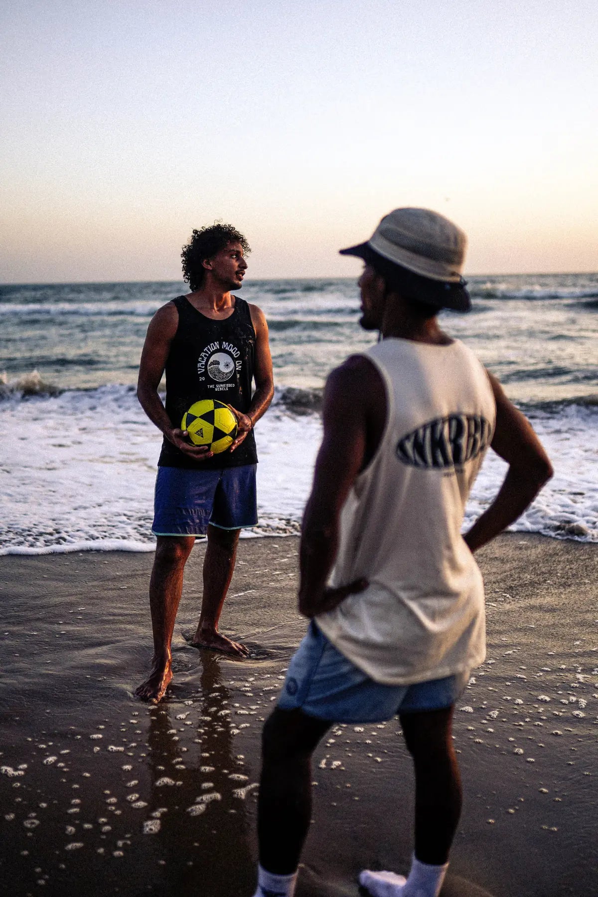 Strandshooting im Abendlicht: Mann im schwarzen und Mann im Natural Raw SNKRBLS Tank Top