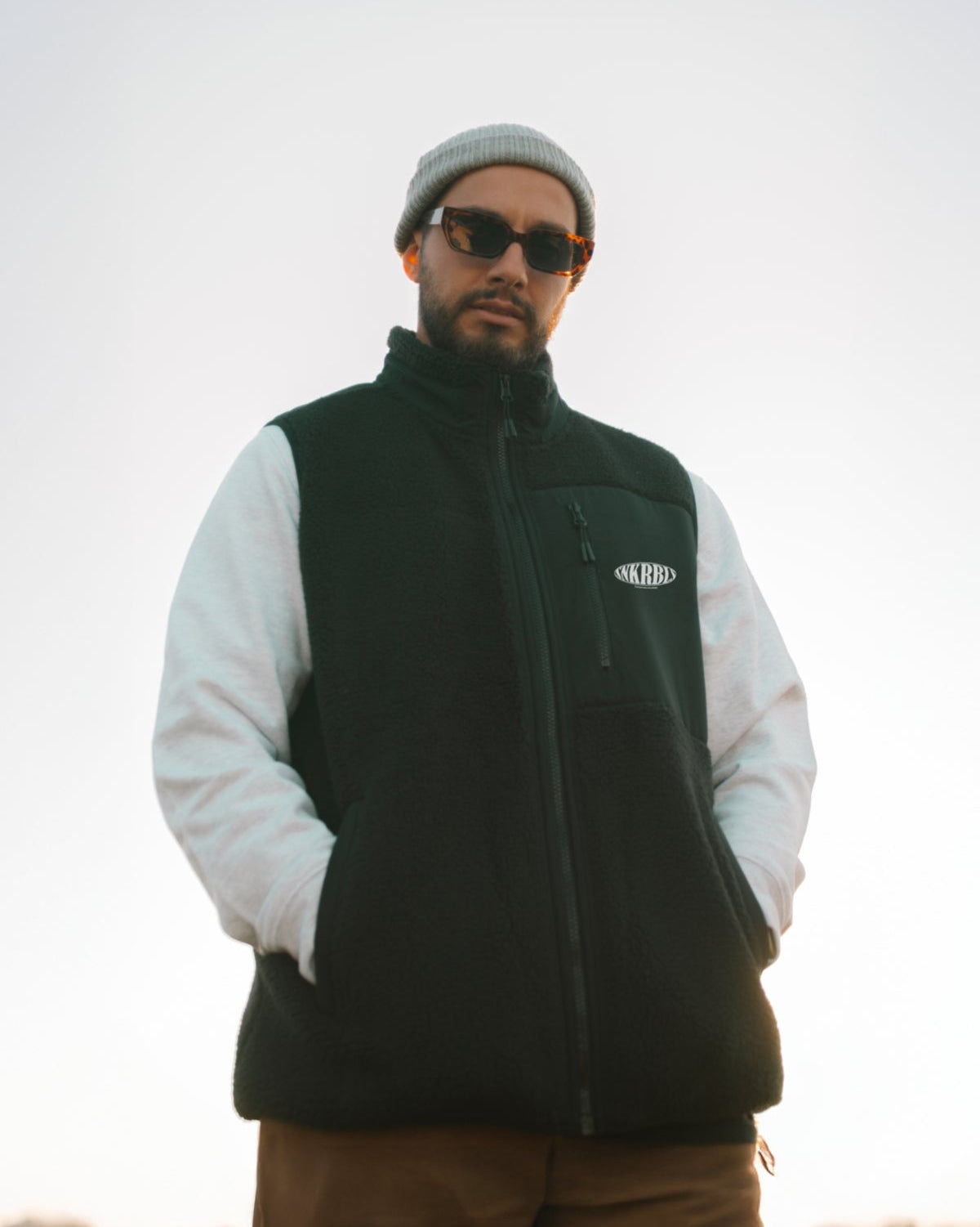 Mann post in Kamera und trägt schwarze fleece Weste