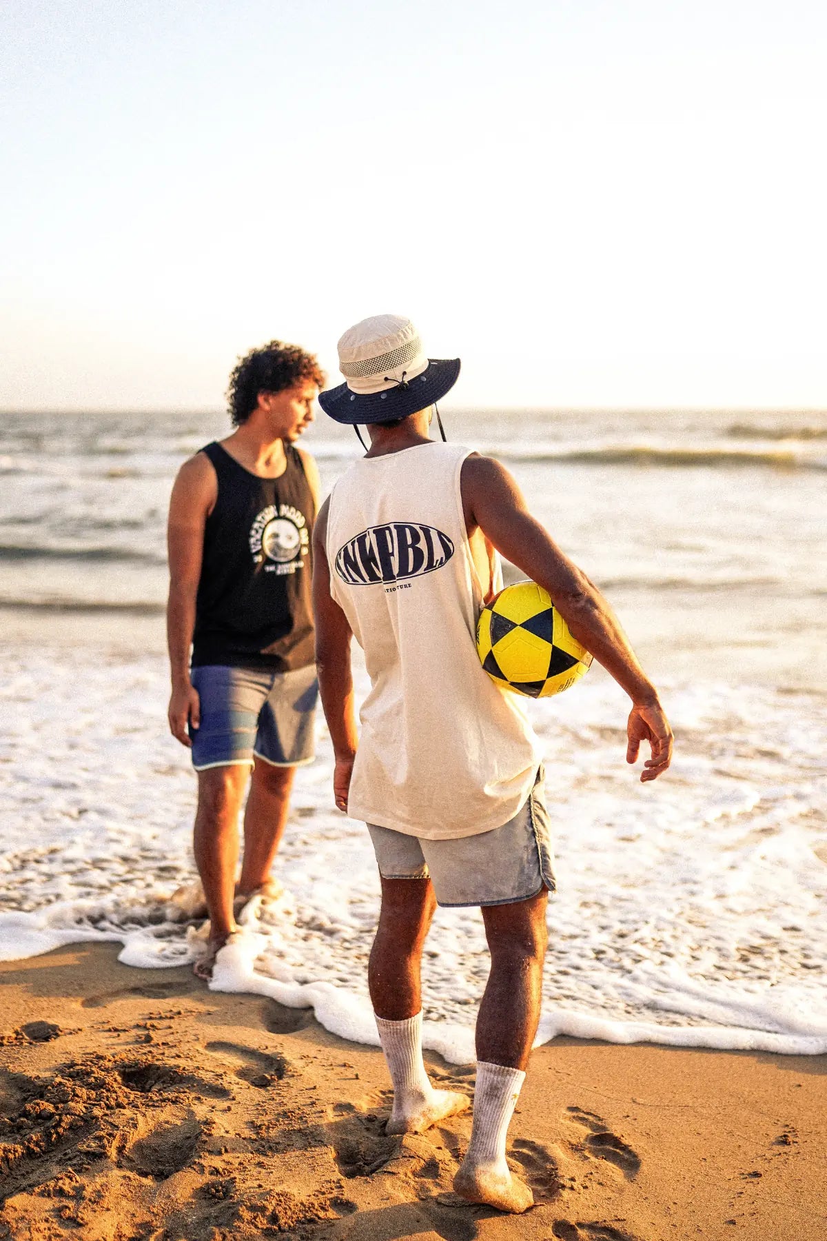 Zwei Freunde am Strand bei Sonnenuntergang mit Ball und SNKRBLS Tank Top – Summer Vibes