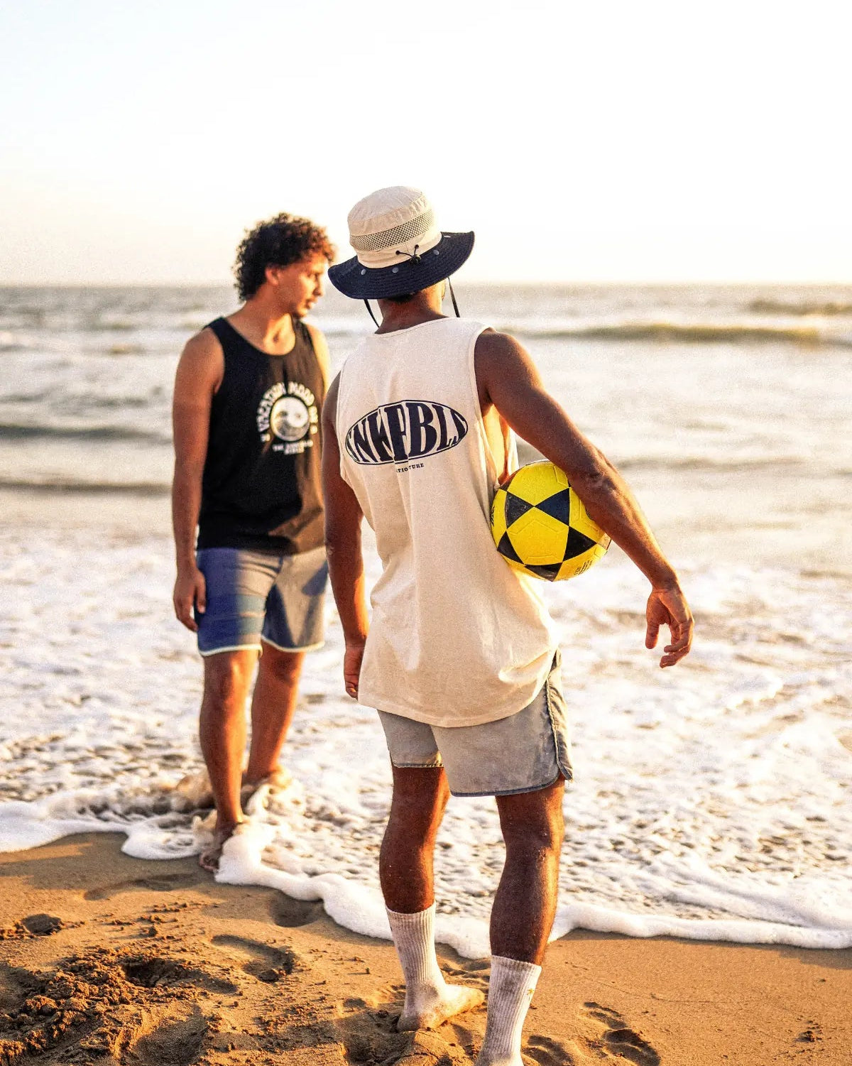 Zwei Freunde am Strand bei Sonnenuntergang mit Ball und SNKRBLS Tank Top – Summer Vibes