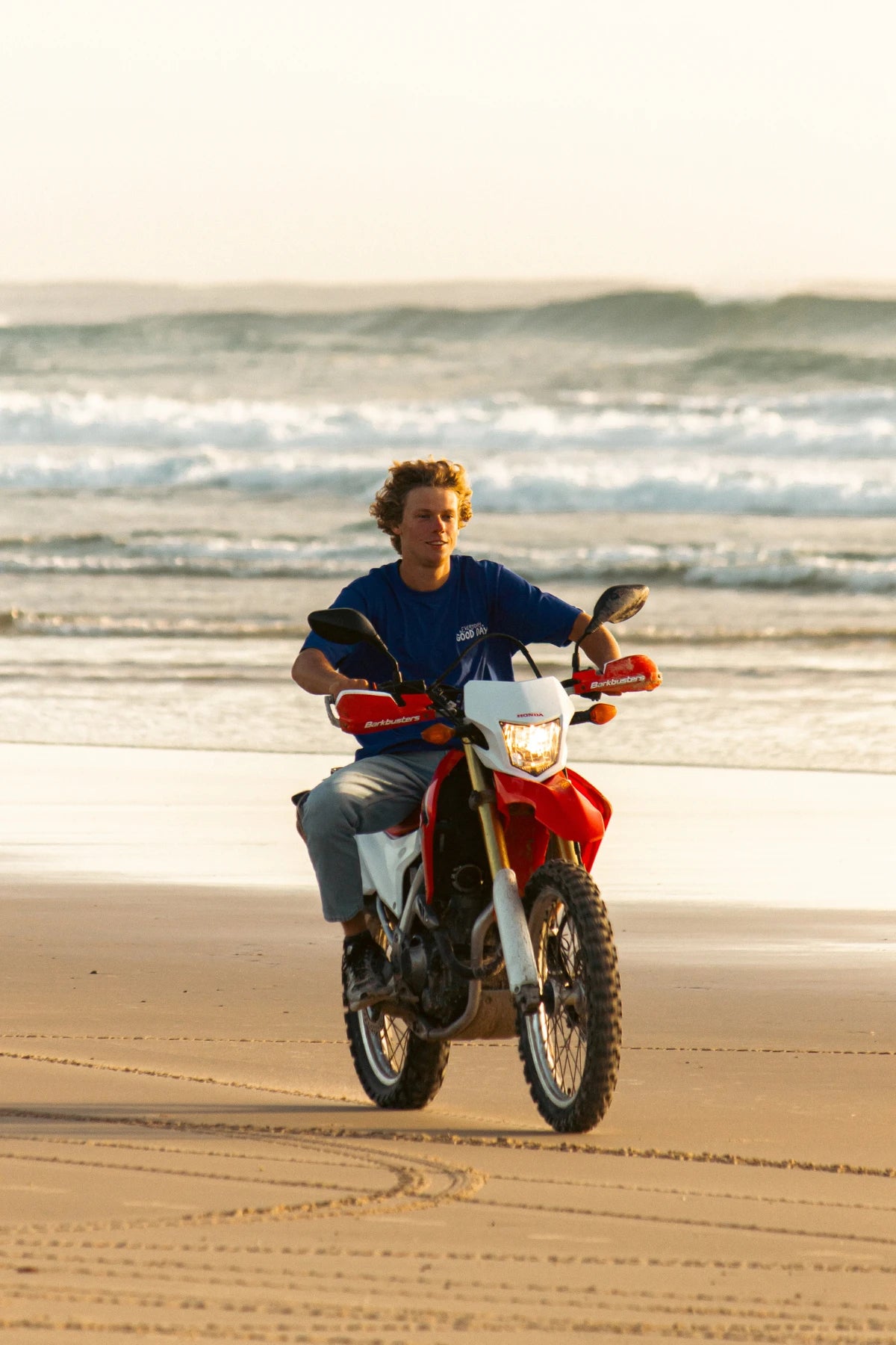 Frontansicht des blauen Oversized Good Day T-Shirts während Motorradfahrt am Meer