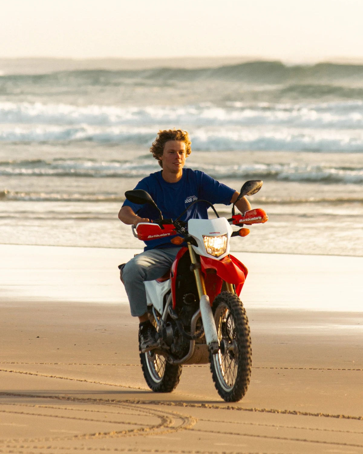 Frontansicht des blauen Oversized Good Day T-Shirts während Motorradfahrt am Meer