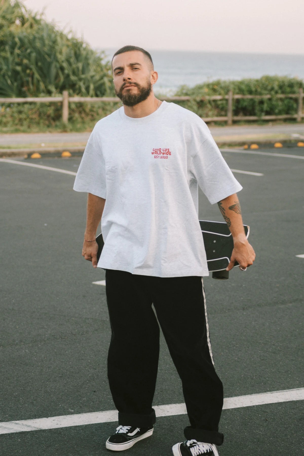 Skater trägt das Goodlife Heavy T-Shirt Cool Grey von The Sunkissed Rebels – entspannter Streetstyle mit Meerblick.