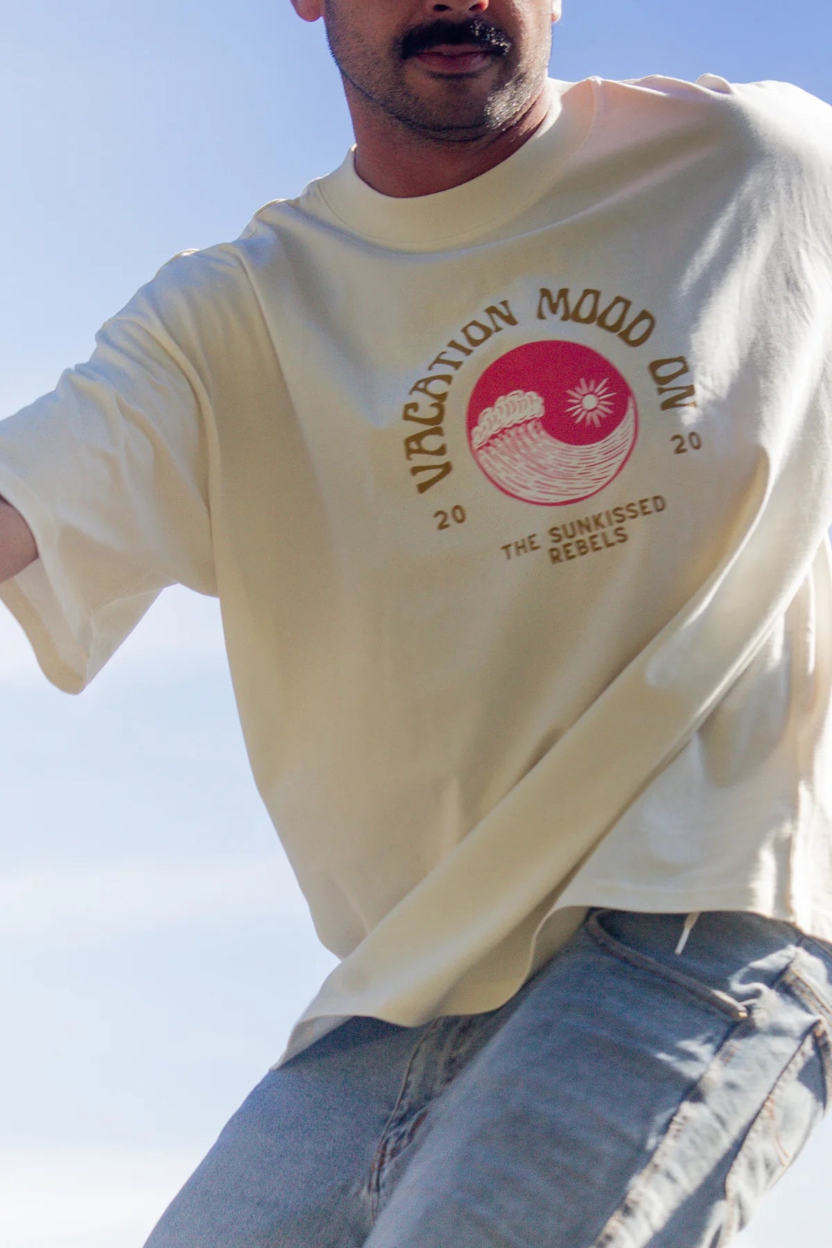 Detailaufnahme des Vacation Mood On Shirts mit Retro-Wellenprint bei Skatebewegung und blauem Himmel