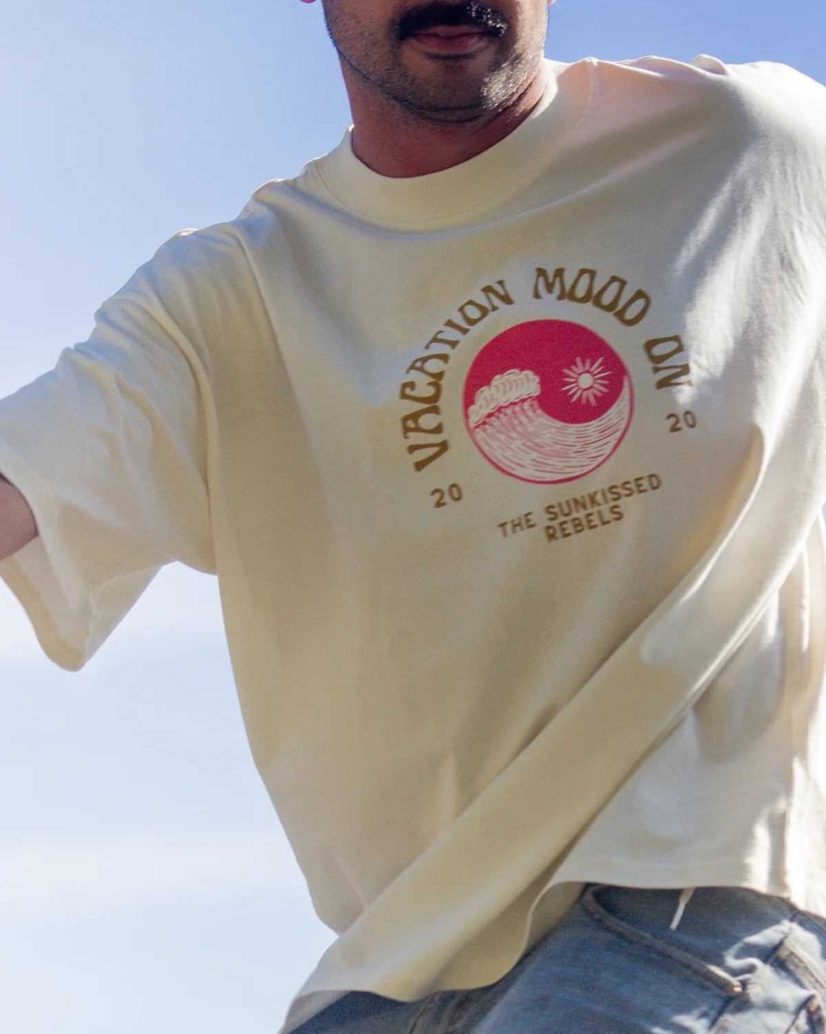 Detailaufnahme des Vacation Mood On Shirts mit Retro-Wellenprint bei Skatebewegung und blauem Himmel