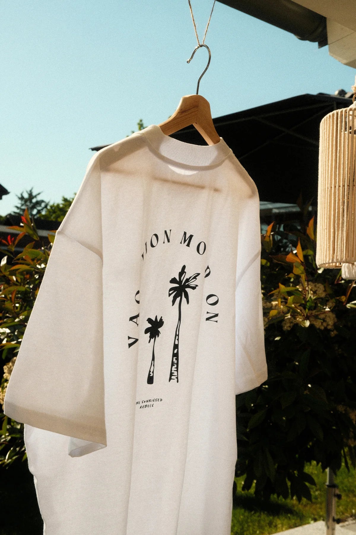 Close-up of the Vacation Mood On T-shirt with black palm tree print hanging in the sun