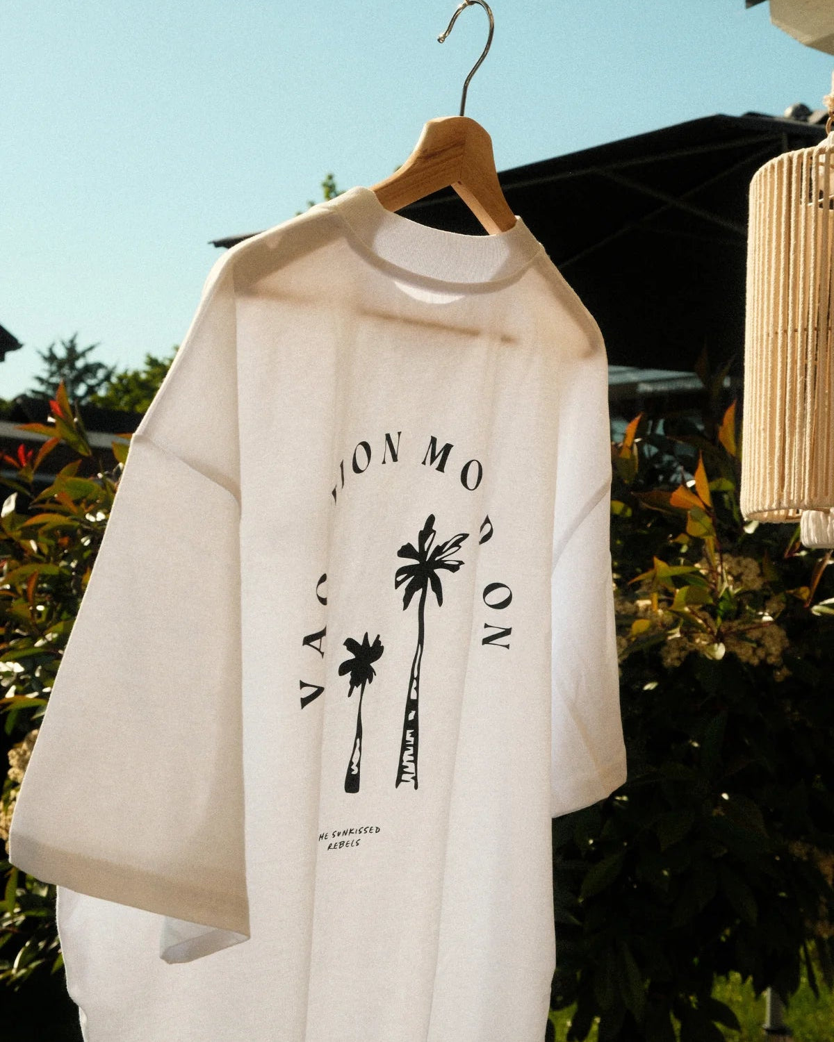 Close-up of the Vacation Mood On T-shirt with black palm tree print hanging in the sun