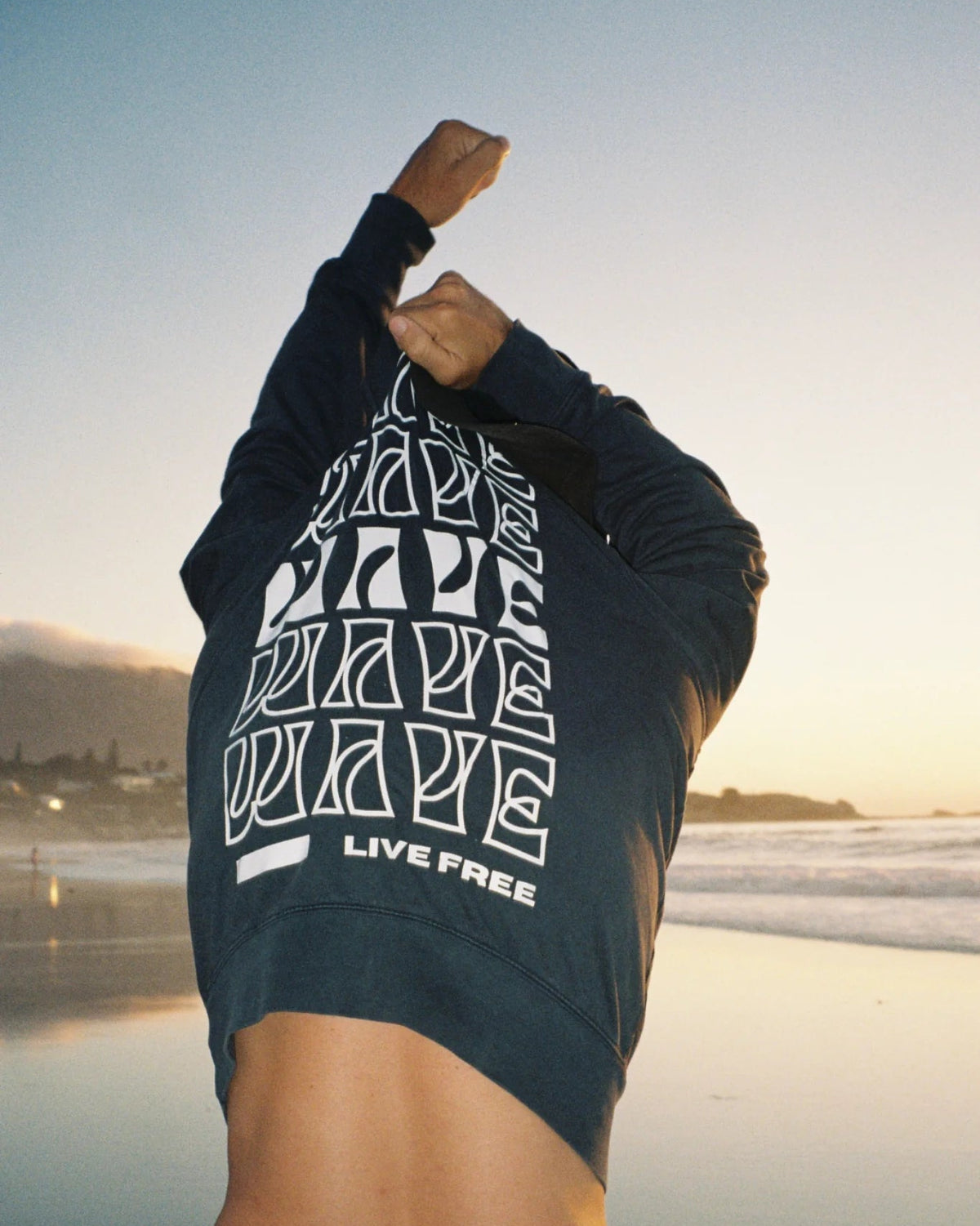 Live Free Vintage Sweater Black von hinten am Meer – minimalistisches Design und nachhaltige Mode