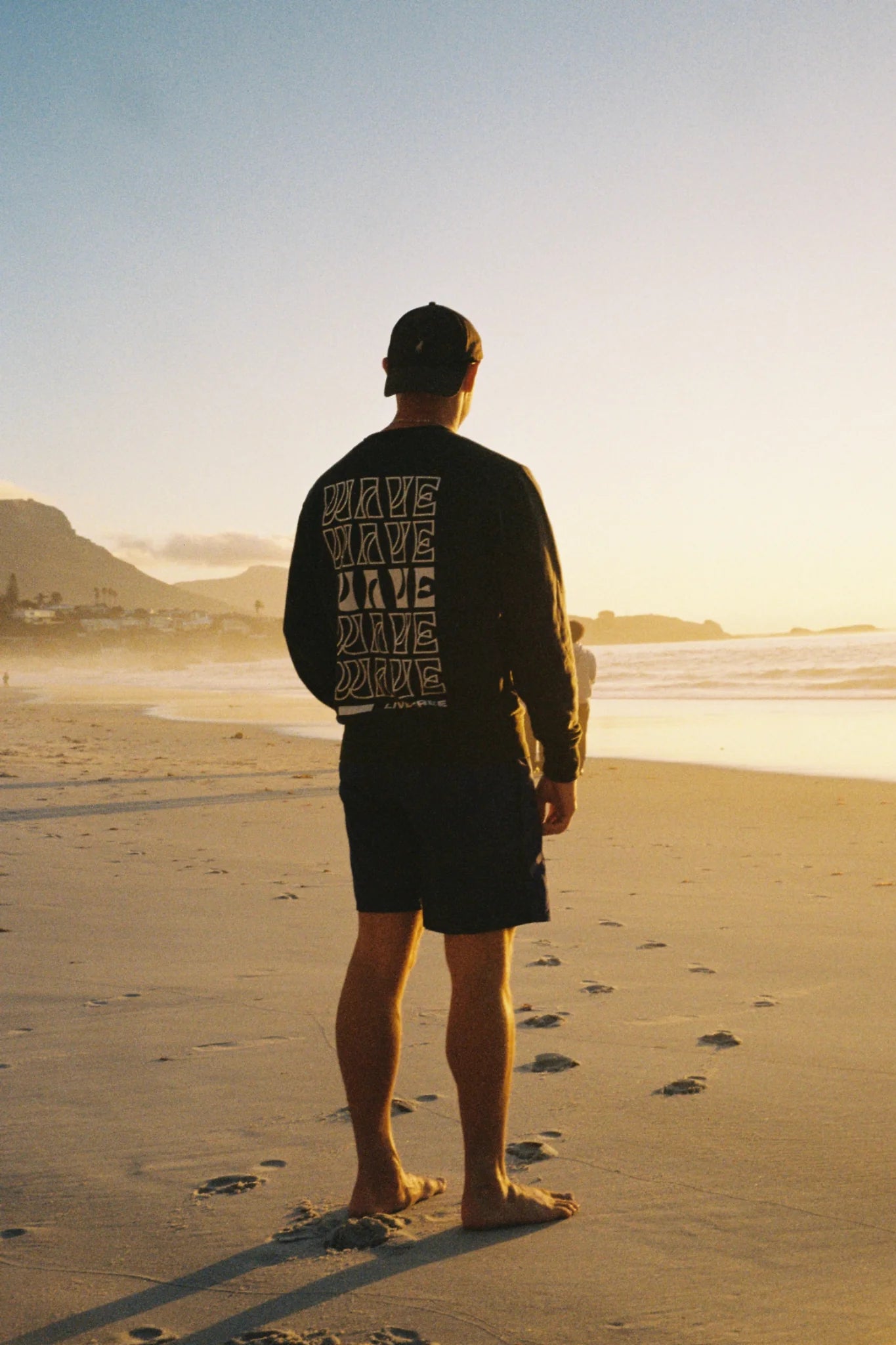 Model trägt Live Free Vintage Sweater Black am Strand bei Sonnenuntergang – nachhaltige Streetwear von The Sunkissed Rebels