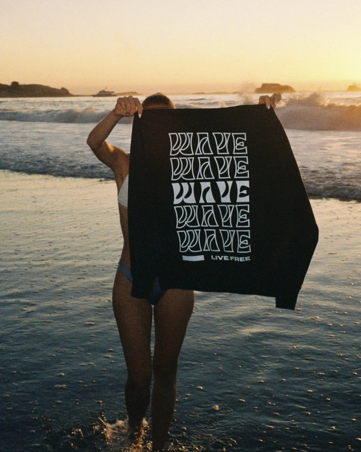 Live Free Vintage Sweater Black wird am Strand präsentiert – fair produzierte Lifestyle-Streetwear