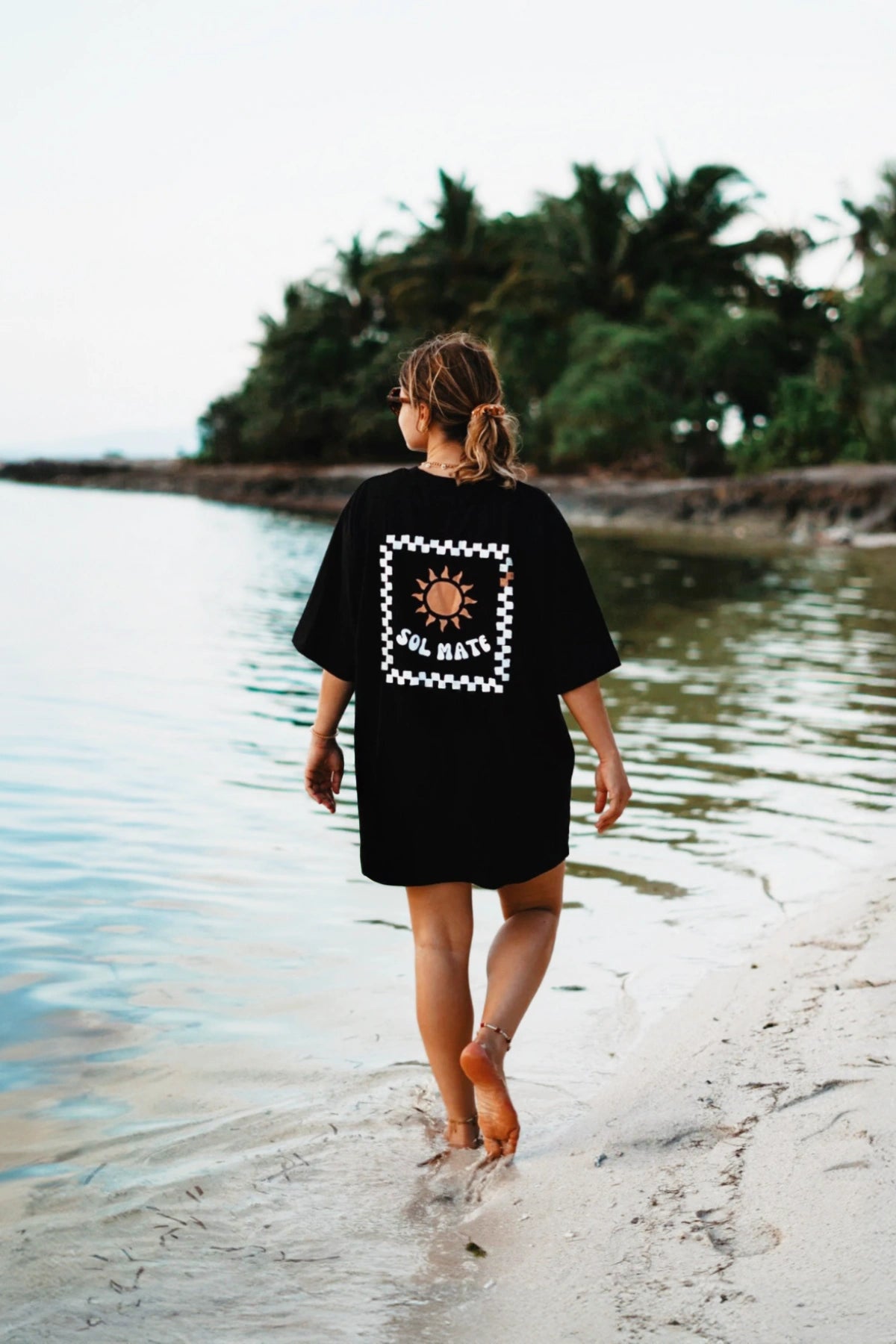 Oversized T-Shirt Sol Mate in Schwarz getragen am Strand bei Sonnenaufgang