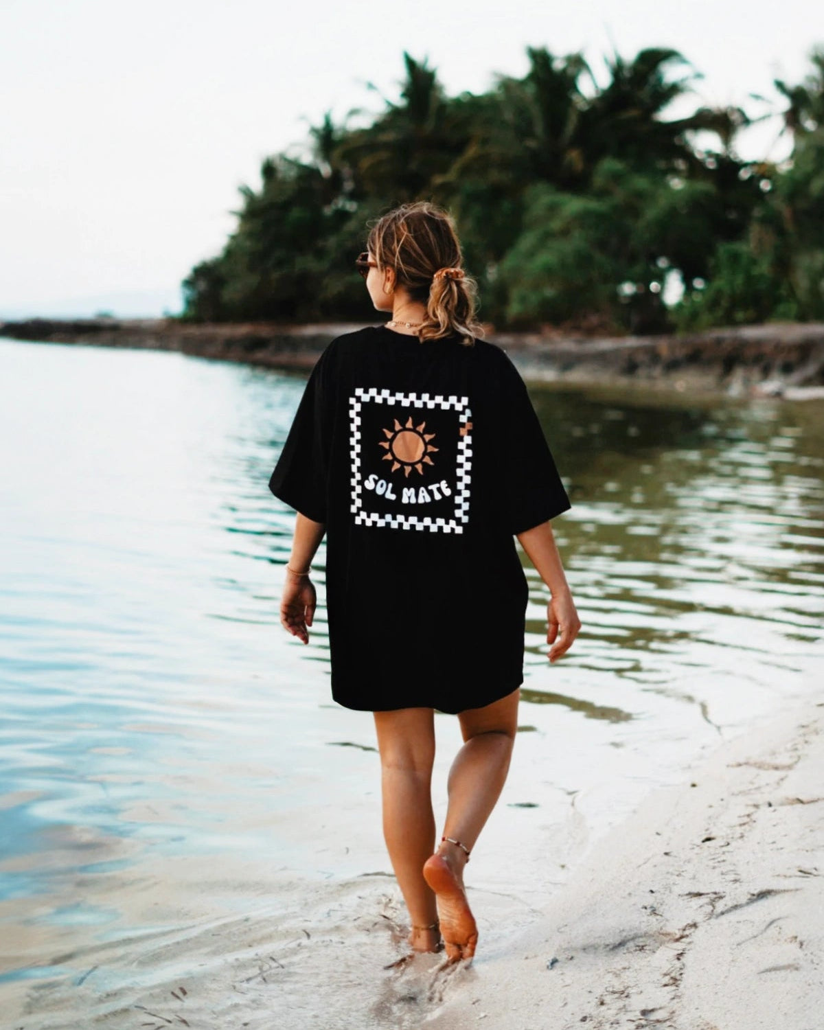 Oversized T-Shirt Sol Mate in Schwarz getragen am Strand bei Sonnenaufgang