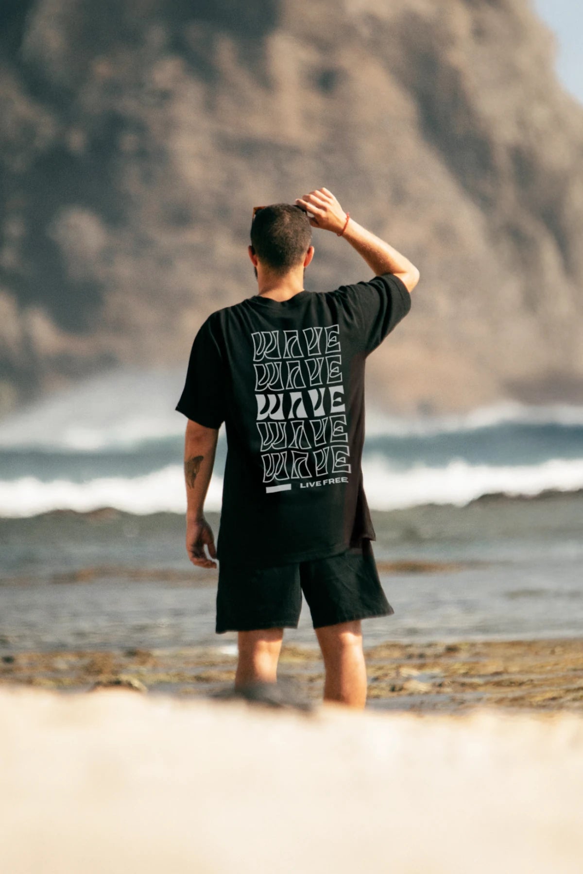 Model am Strand im schwarzen Live Free T-Shirt – Rückansicht von The Sunkissed Rebels