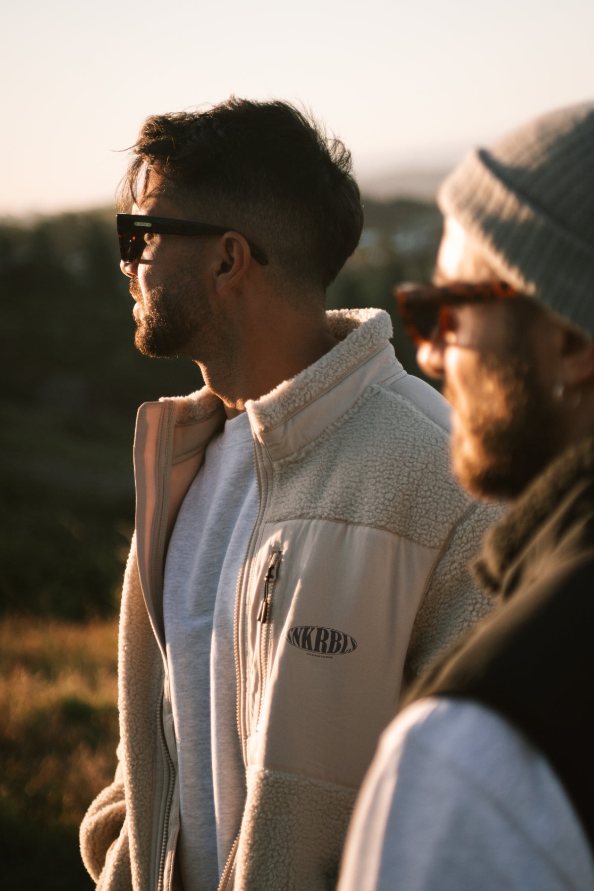 Mann mit beiger warmen fleece jacke schaut den Sonnenuntergang