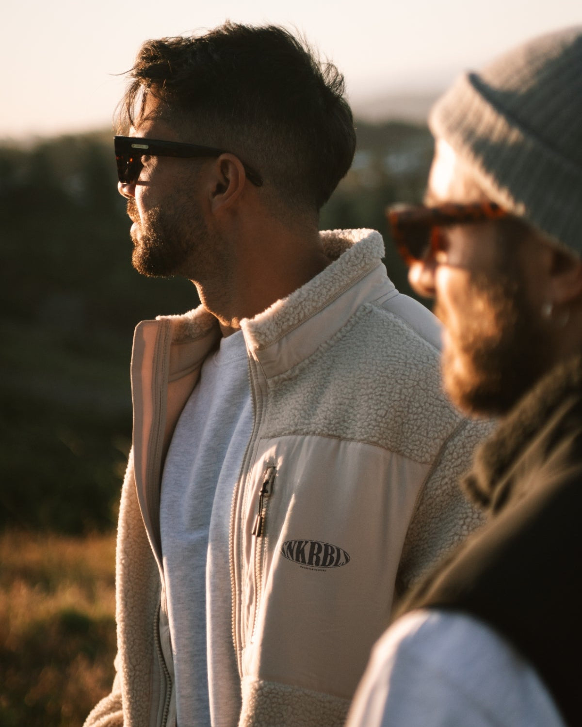 Mann mit beiger warmen fleece jacke schaut den Sonnenuntergang