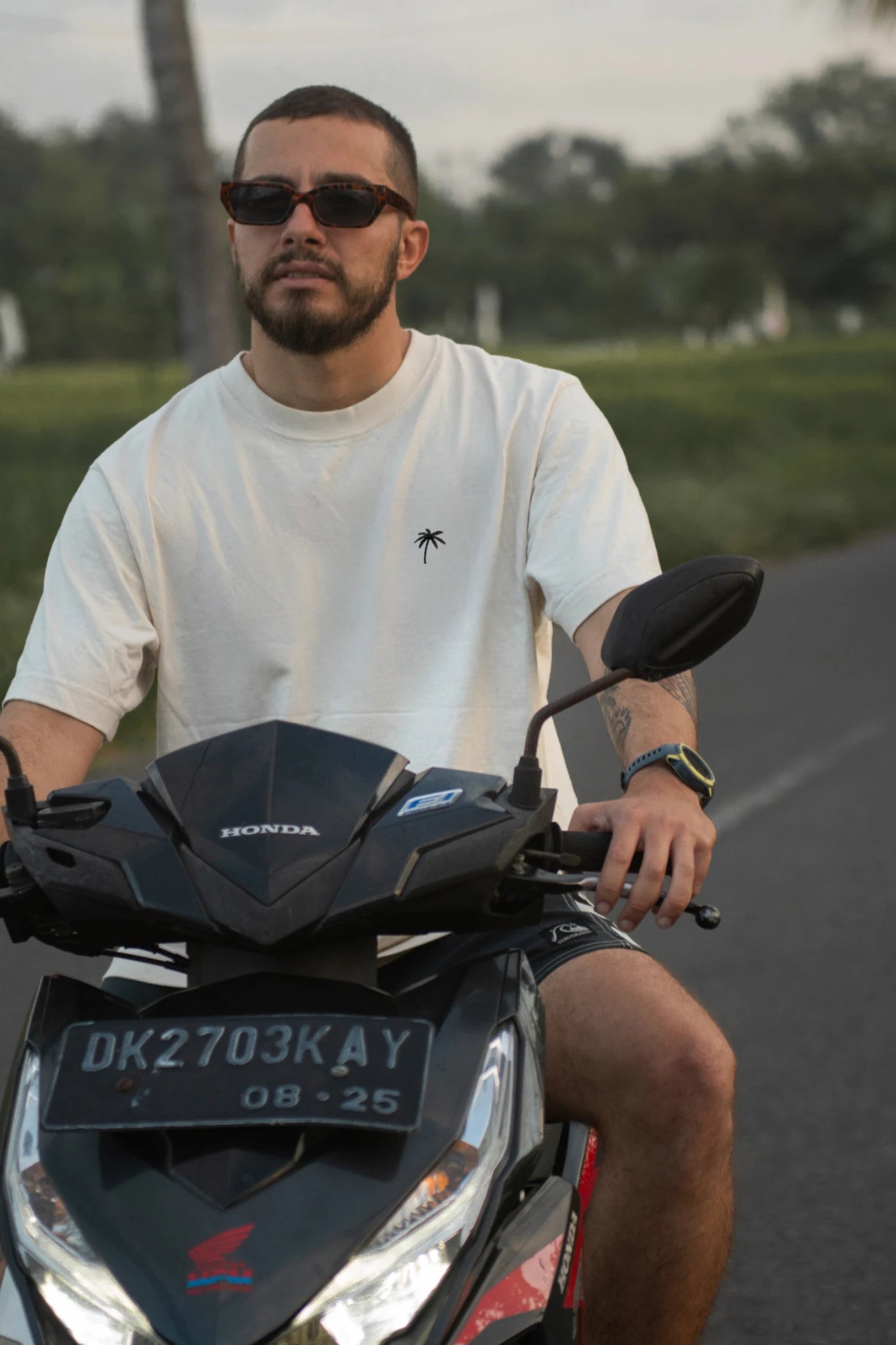 Oversized T-Shirt Natural Raw Palm Tree von The Sunkissed Rebels beim Rollerfahren im tropischen Lifestyle