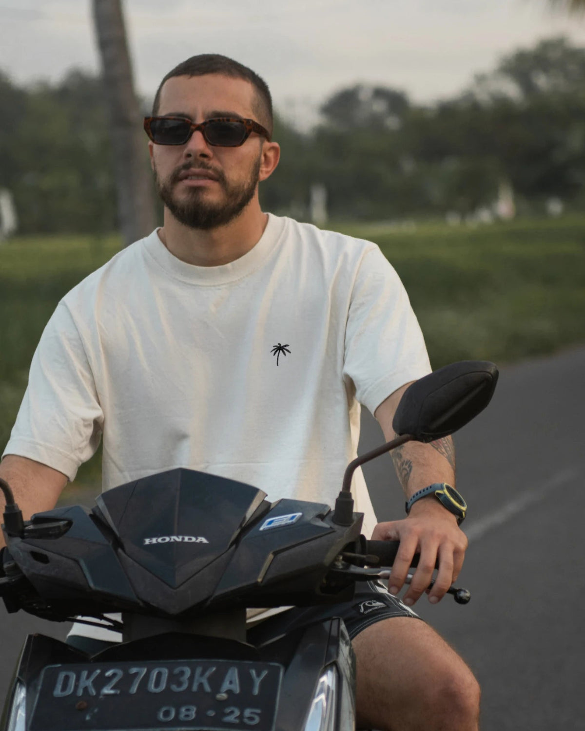 Oversized T-Shirt Natural Raw Palm Tree von The Sunkissed Rebels beim Rollerfahren im tropischen Lifestyle