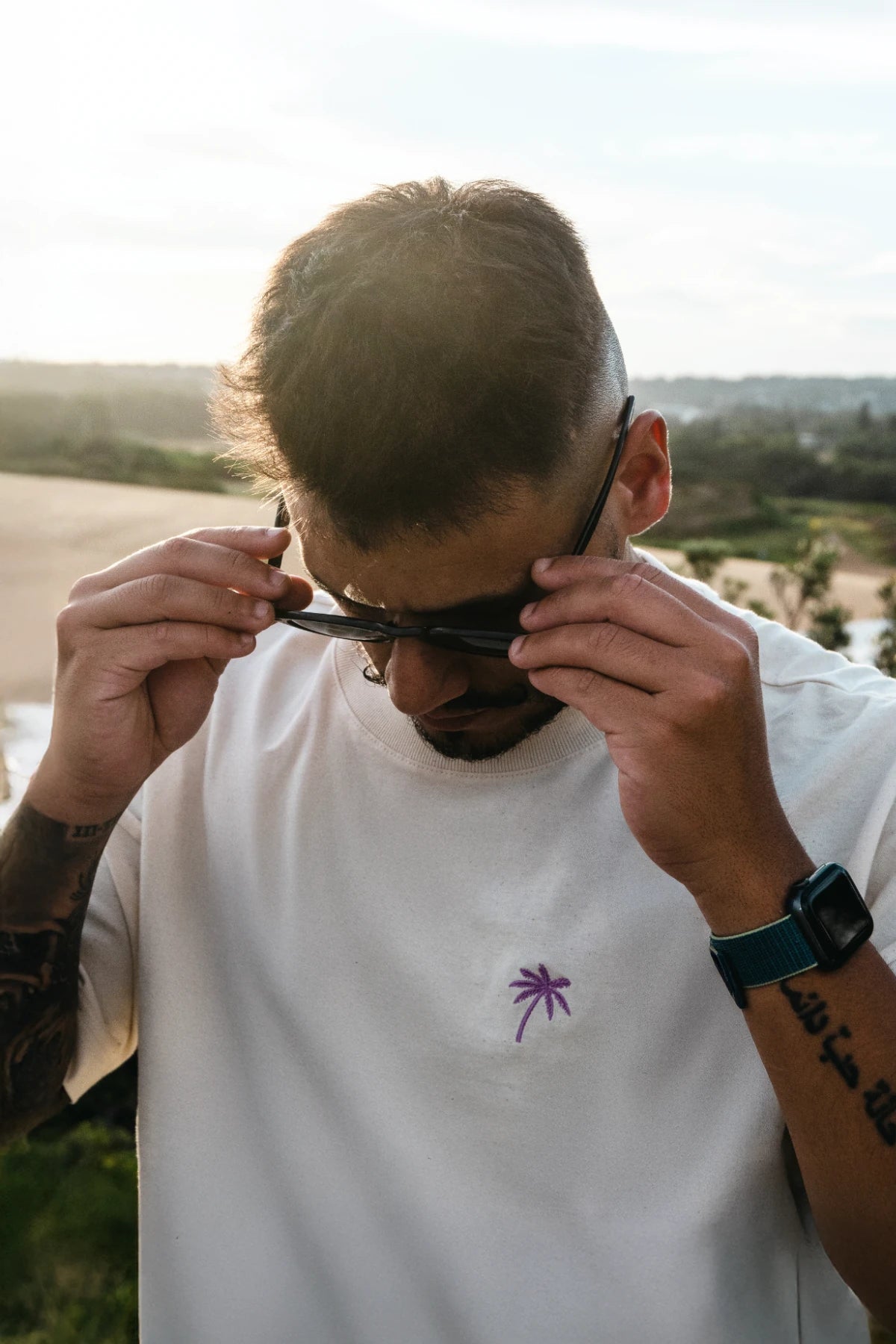 ahaufnahme Oversized T-Shirt mit Palmen-Stick, Mann setzt Sonnenbrille auf